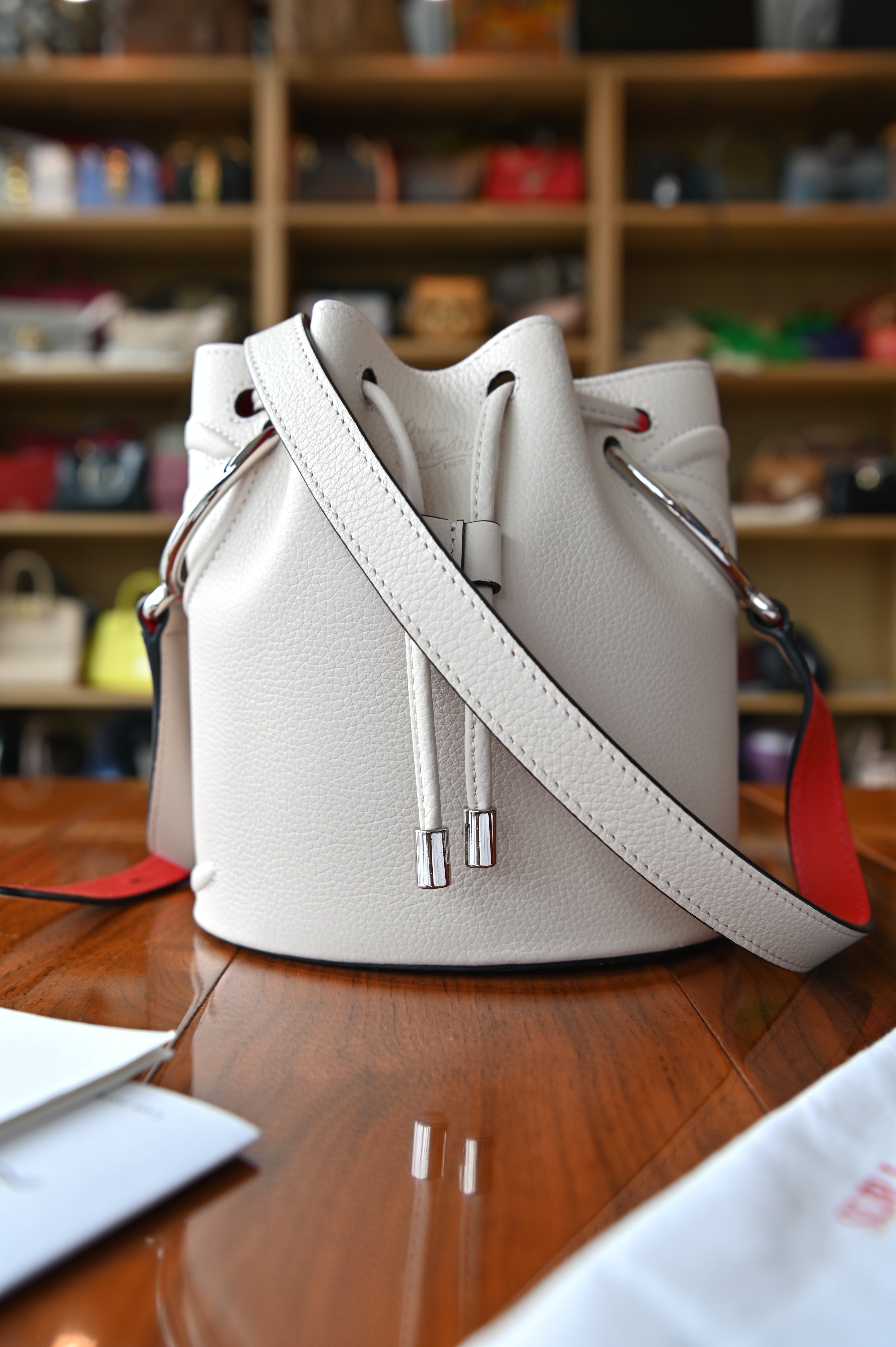 Authentic Christian Louboutin By My Side Light Pink Bucket Bag shown from an angled view highlighting its grained leather construction.