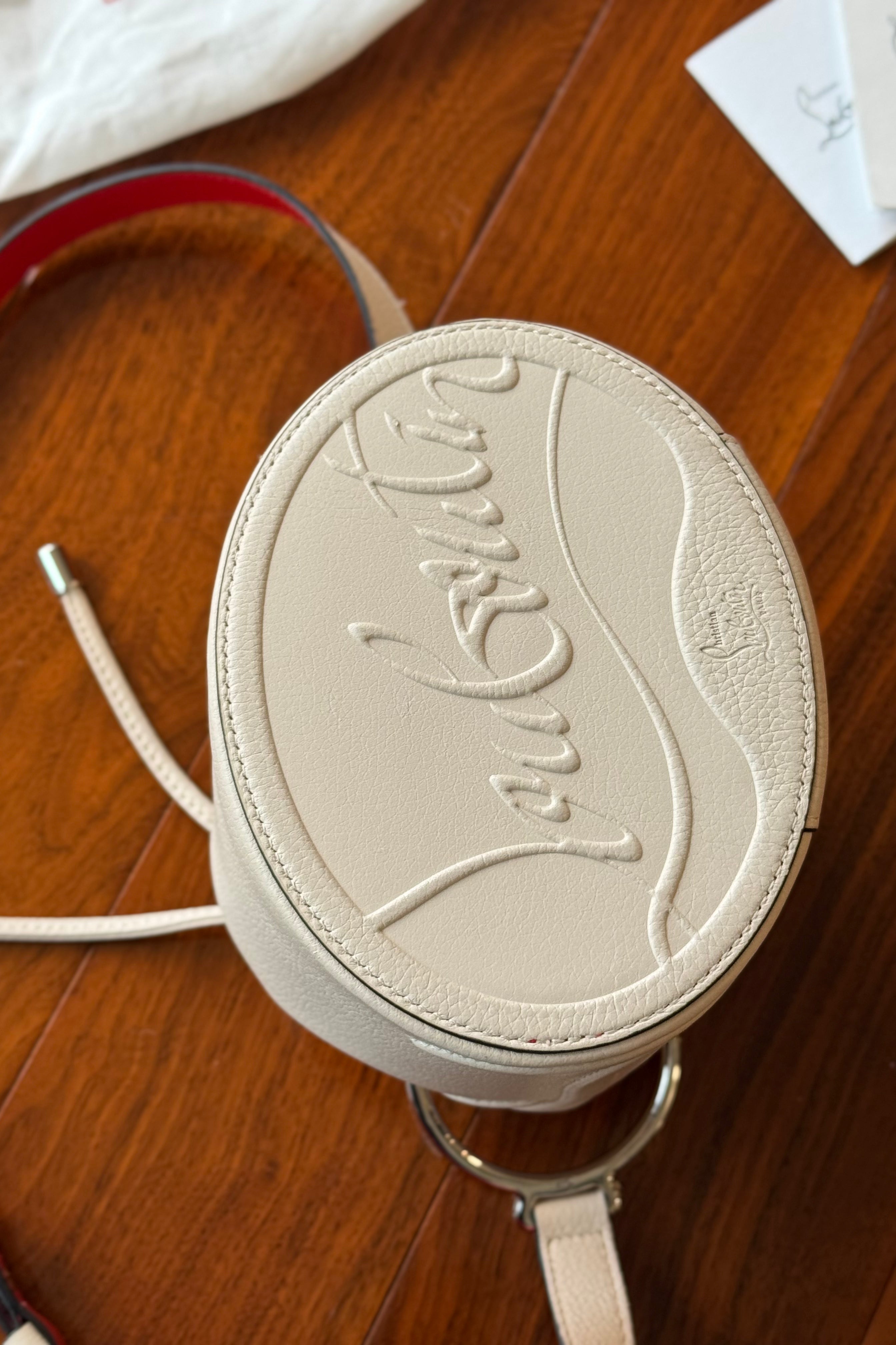 Authentic Christian Louboutin By My Side Bucket Bag showing the leather base with embossed Christian Louboutin signature branding.