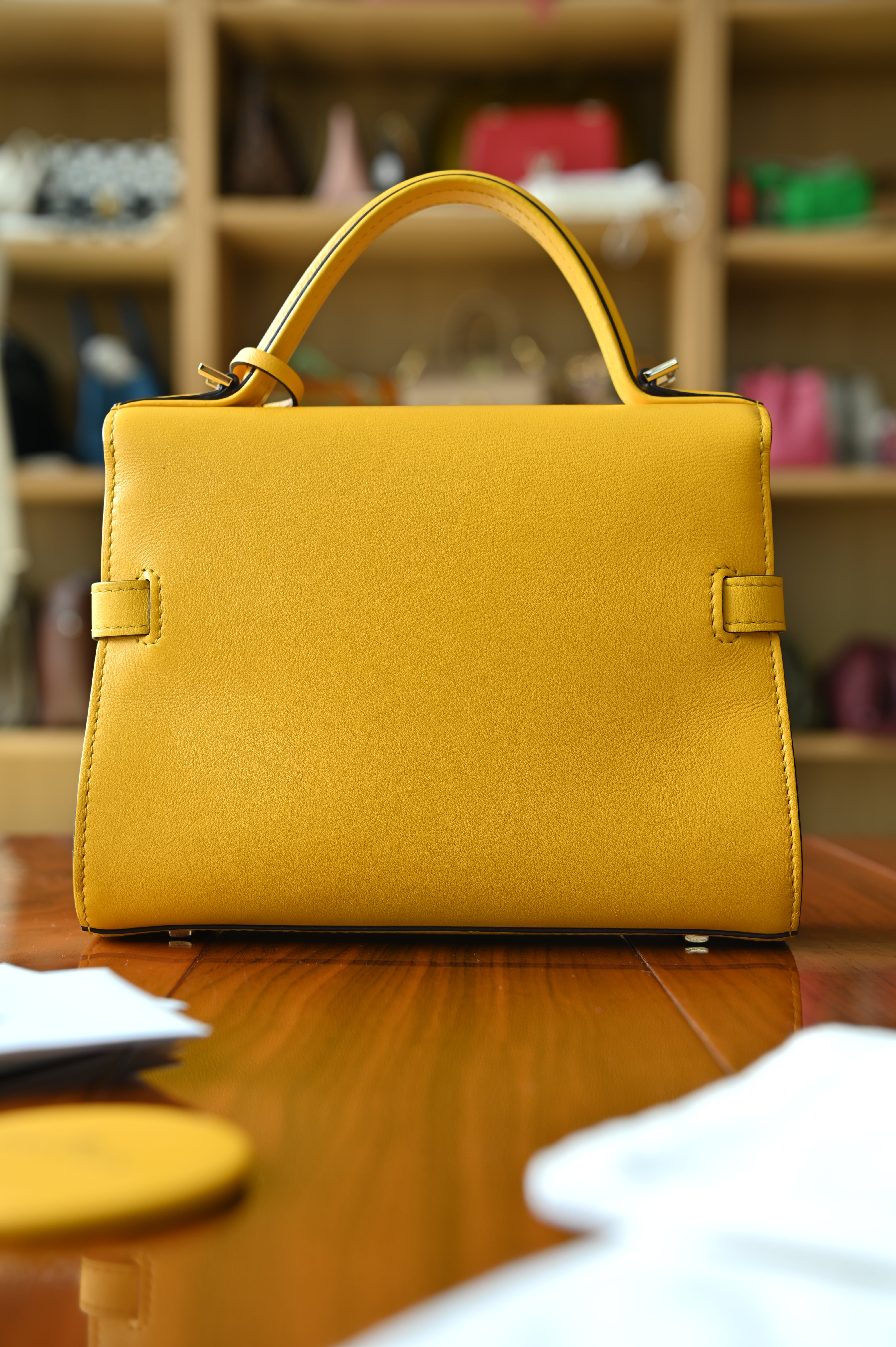 Authentic Delvaux Tempête Mini Souple Safra Yellow Leather Top Handle Bag shown from a rear angled view highlighting its structured shape and premium leather finish.