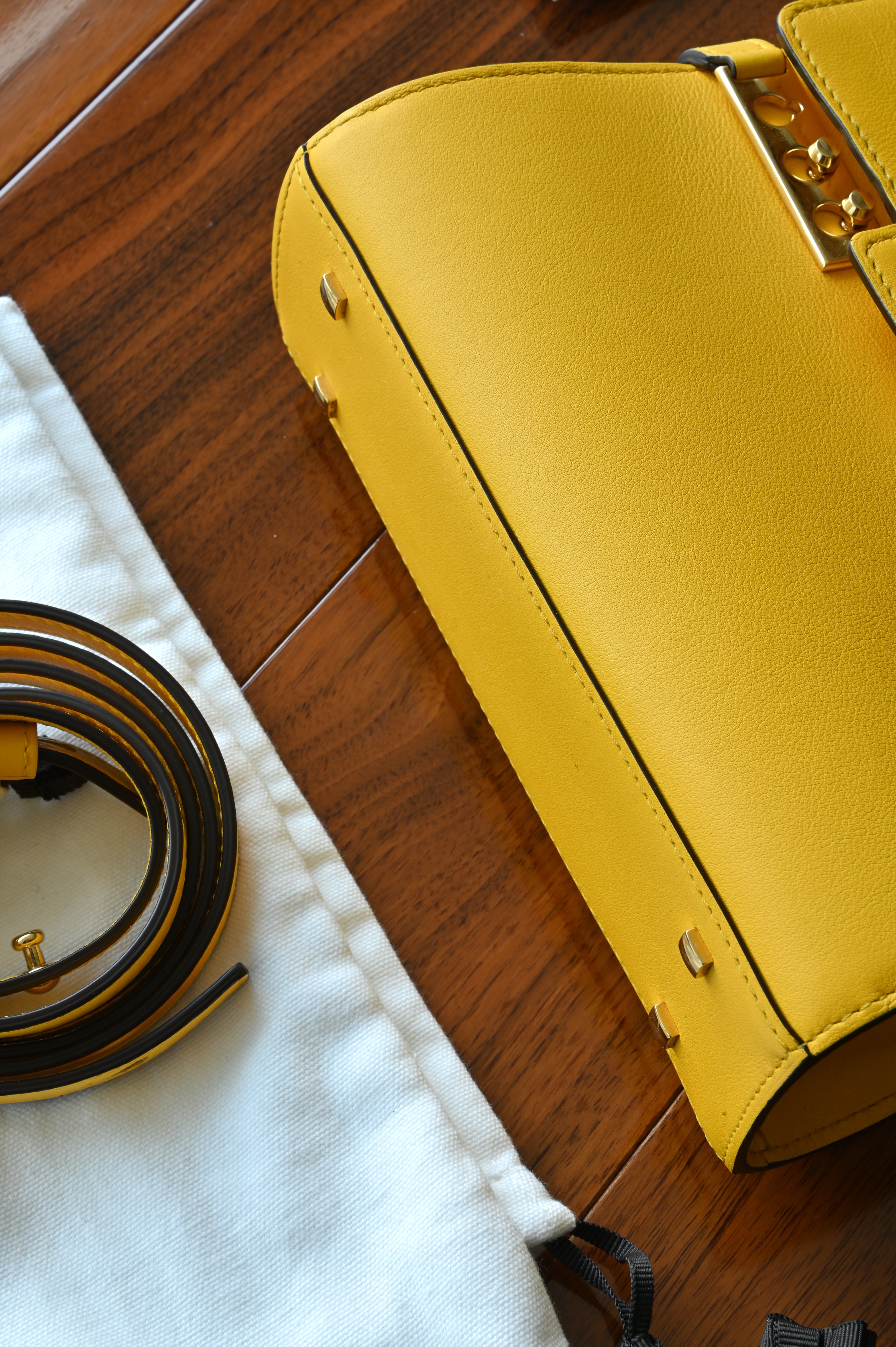 Authentic Delvaux Tempête Mini Souple Safra Yellow Leather Top Handle Bag showing the structured leather base with protective feet and precise craftsmanship.