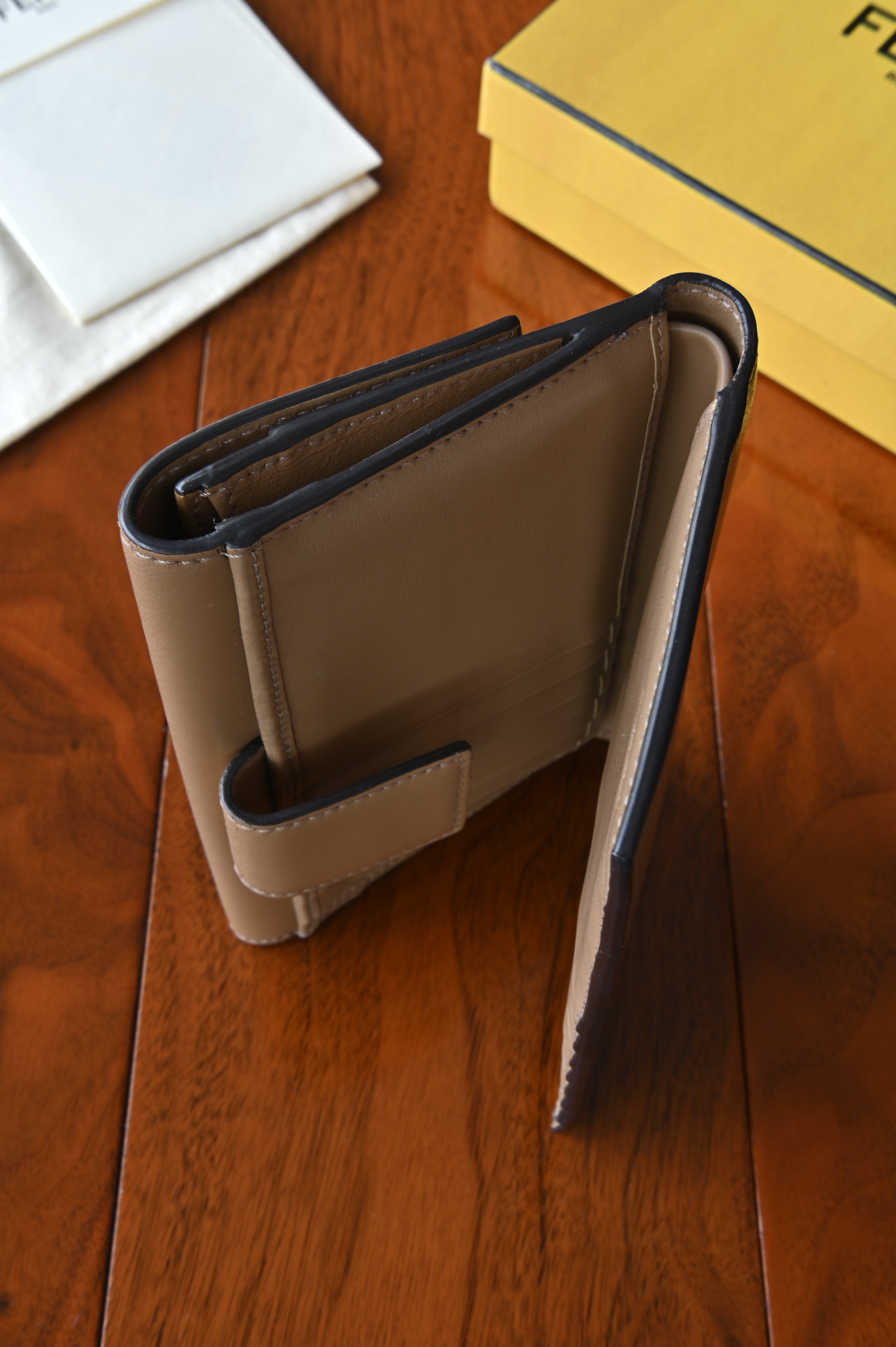 Side profile of the authentic Fendi beige leather continental wallet displaying its slim continental silhouette.