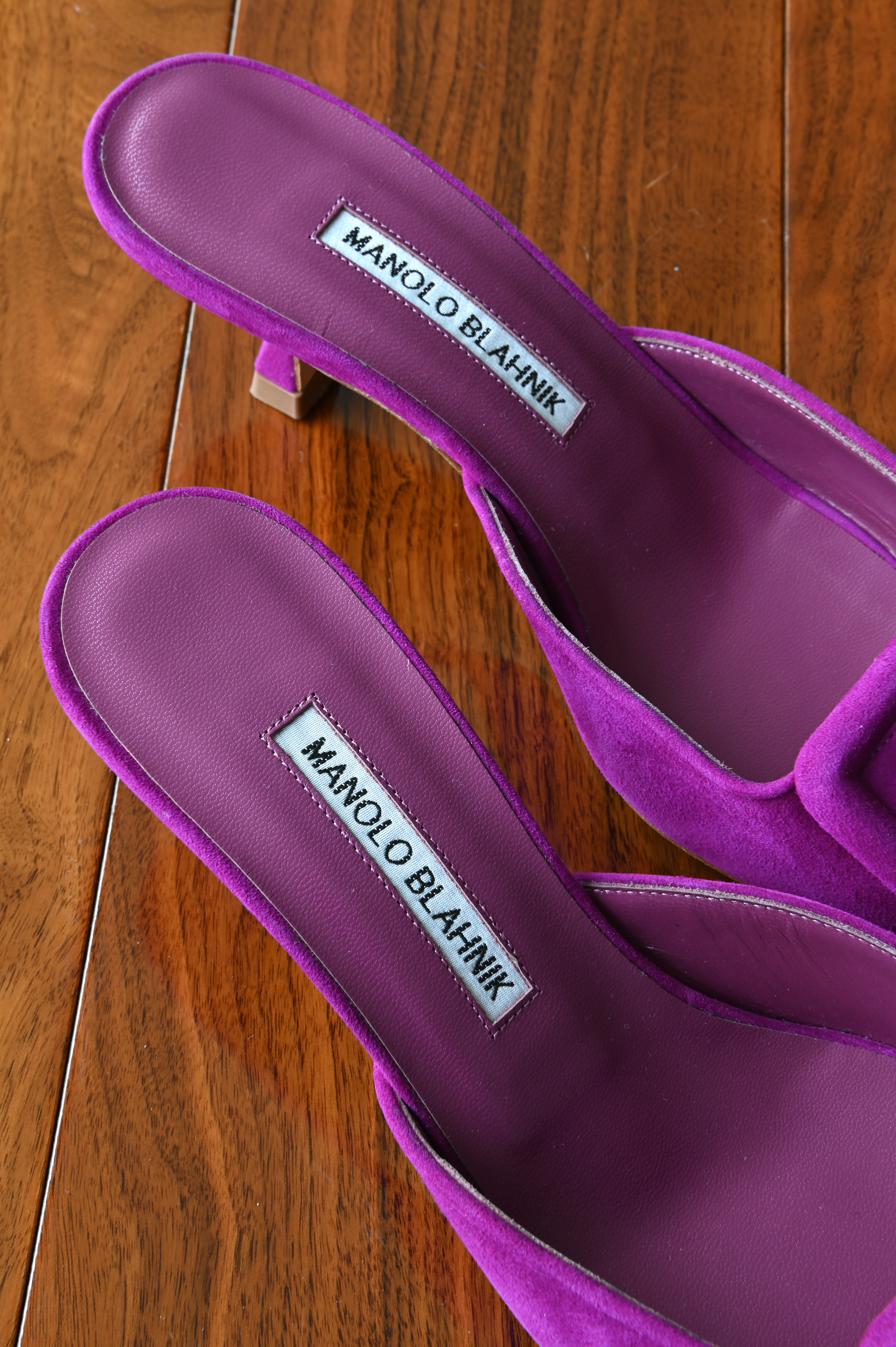 Close-up of the Manolo Blahnik logo on the purple leather footbeds, highlighting the premium craftsmanship and luxurious suede finish