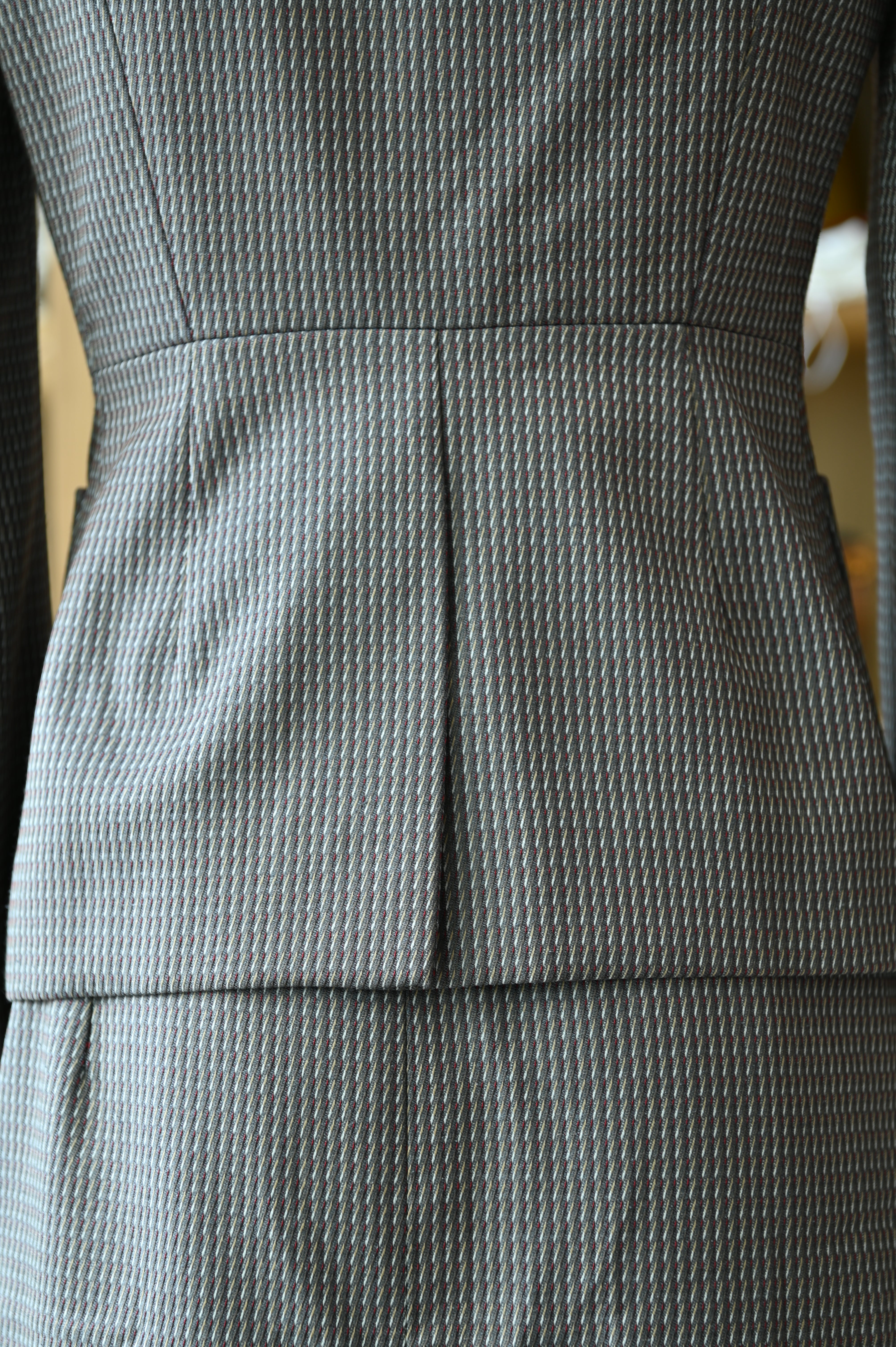 Close-up of the authentic Miu Miu Grey Checked Two-Piece Skirt Suit highlighting the fitted waist and rear tailoring of the blazer.