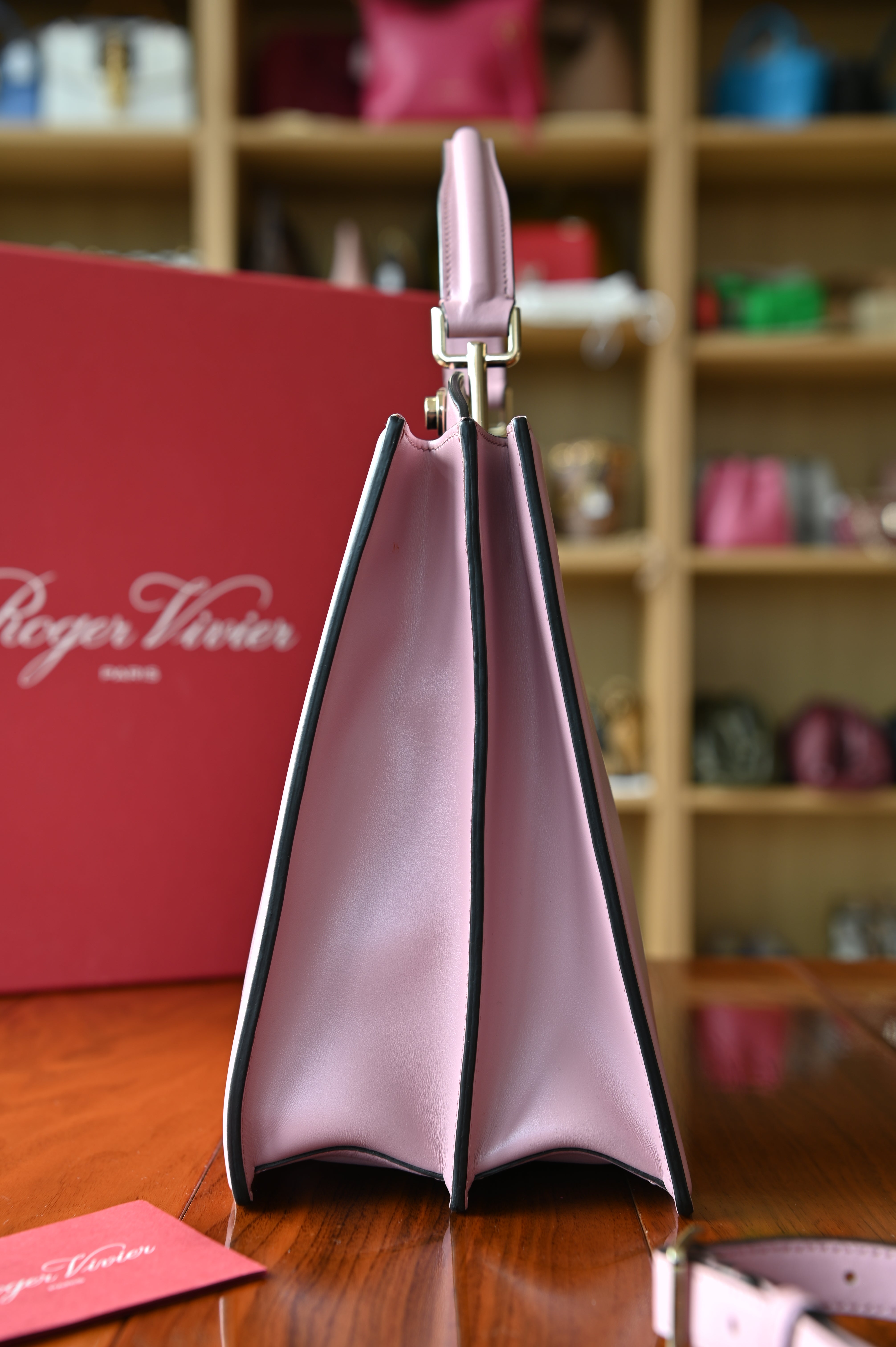 Right side profile of the authentic Roger Vivier Viv’ Cabas Pink Leather Top Handle Bag in smooth pink leather.