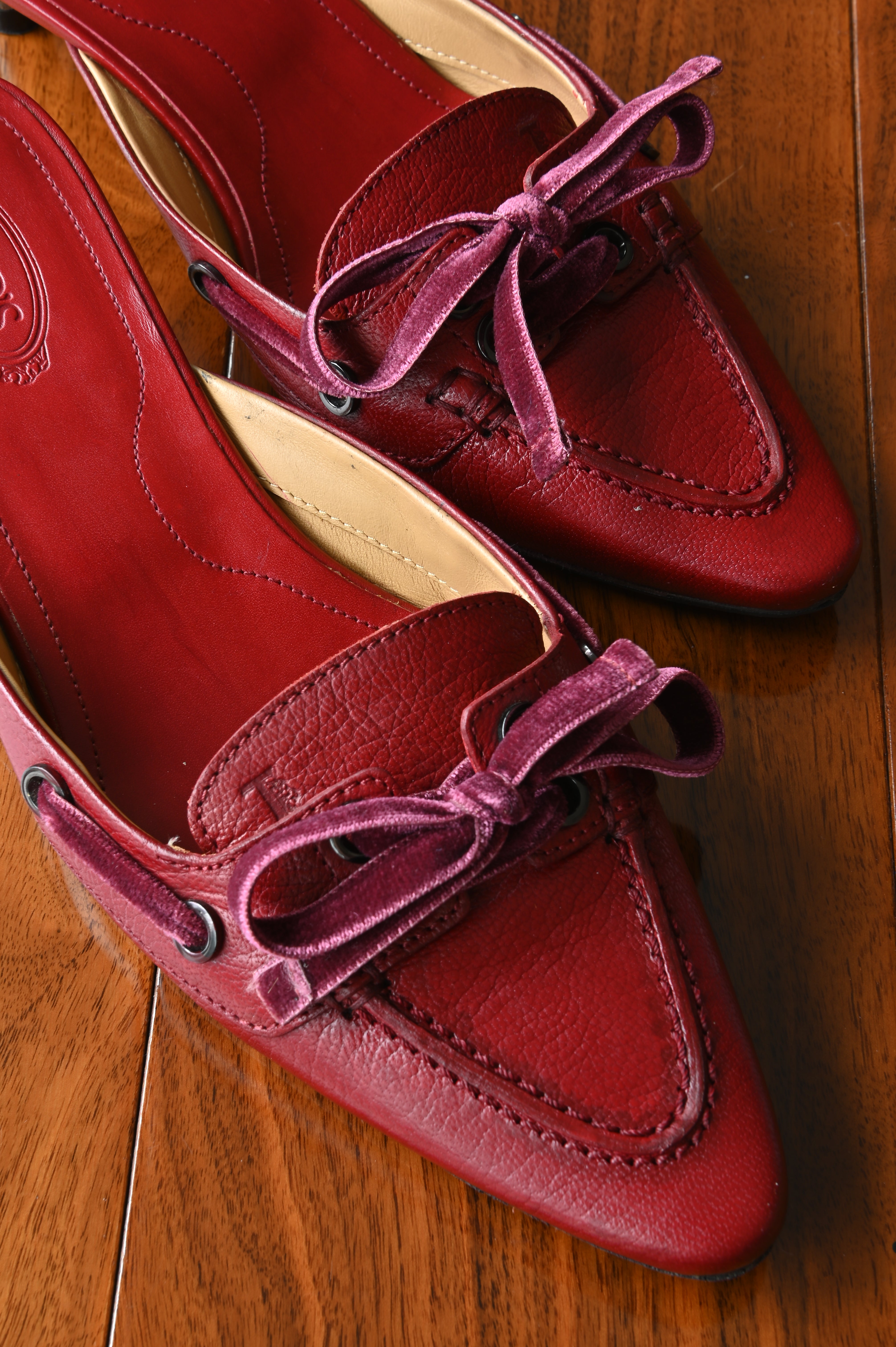 Close-up of the burgundy leather and velvet bow detailing highlighting the overall excellent condition of the Tod’s mules.