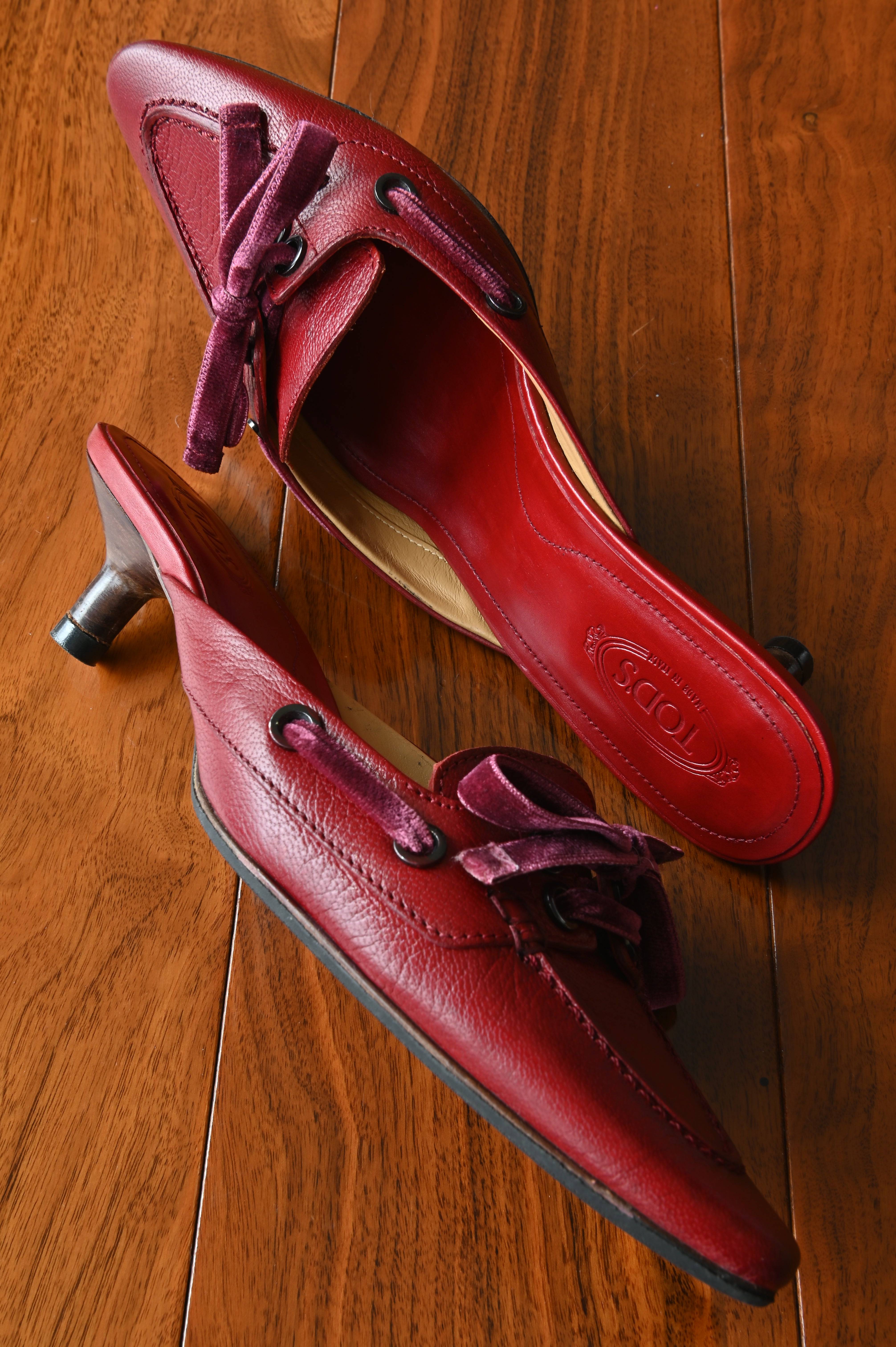 Top angled view of authentic Tod’s leather kitten heel mules highlighting the leather-lined interior and velvet bow detail.