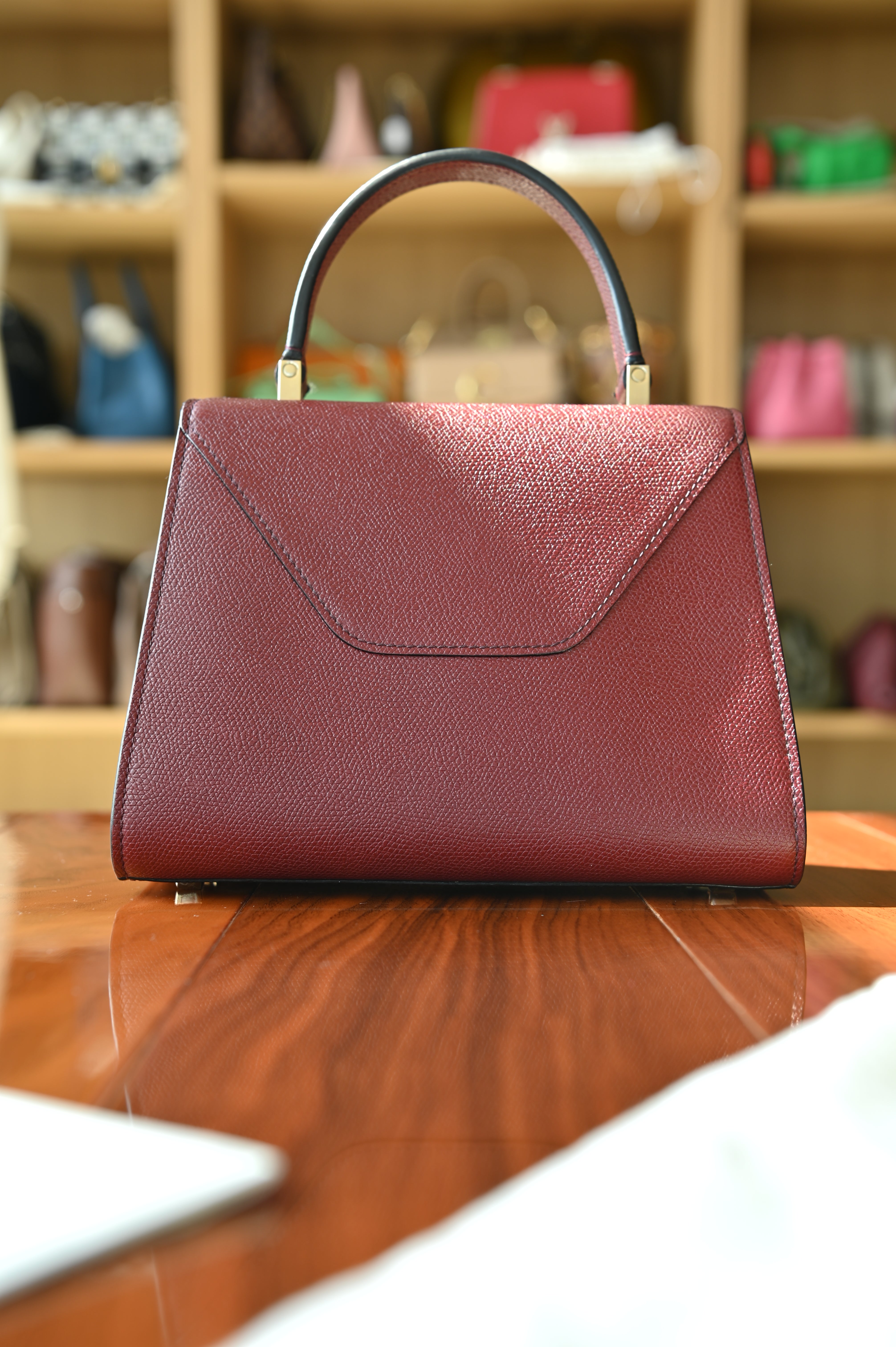 Rear view of the authentic Valextra Iside top handle bag showcasing the clean structured silhouette in burgundy grained leather.