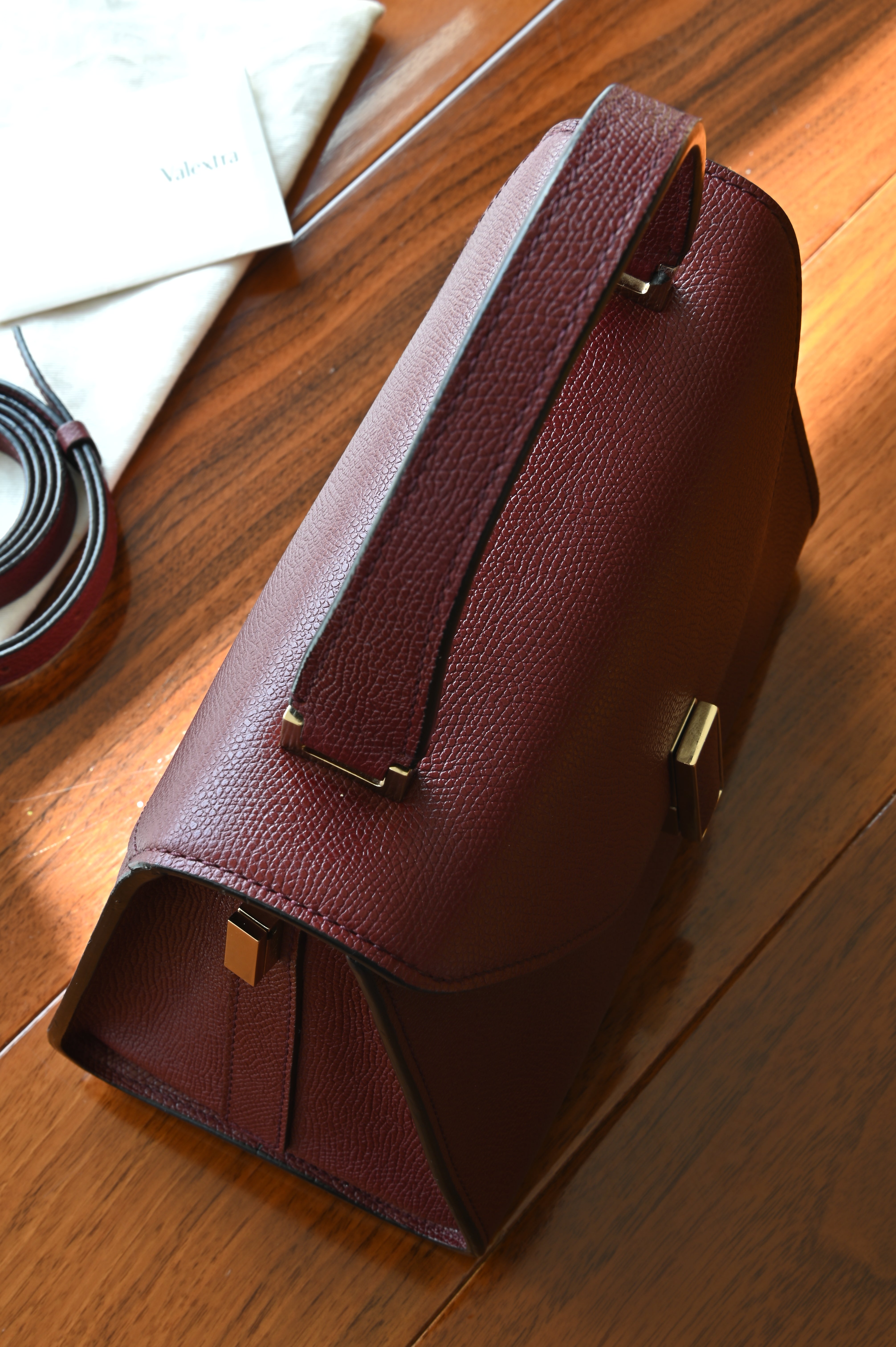 Bottom view of the authentic Valextra Iside handbag showing the protective metal feet and well-maintained burgundy grained leather base.