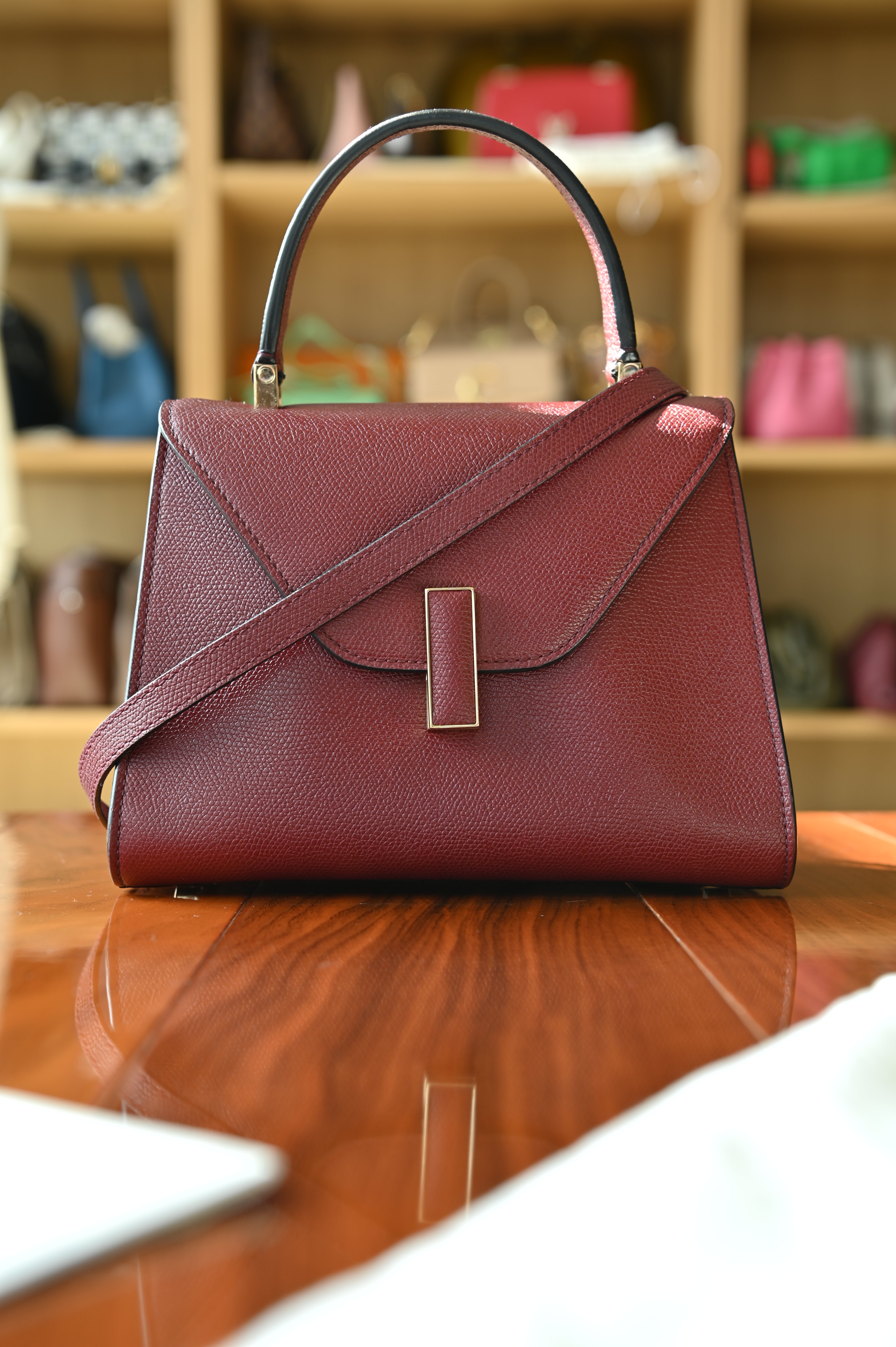 Front view of the authentic Valextra Iside handbag with detachable shoulder strap attached, crafted in burgundy grained leather.