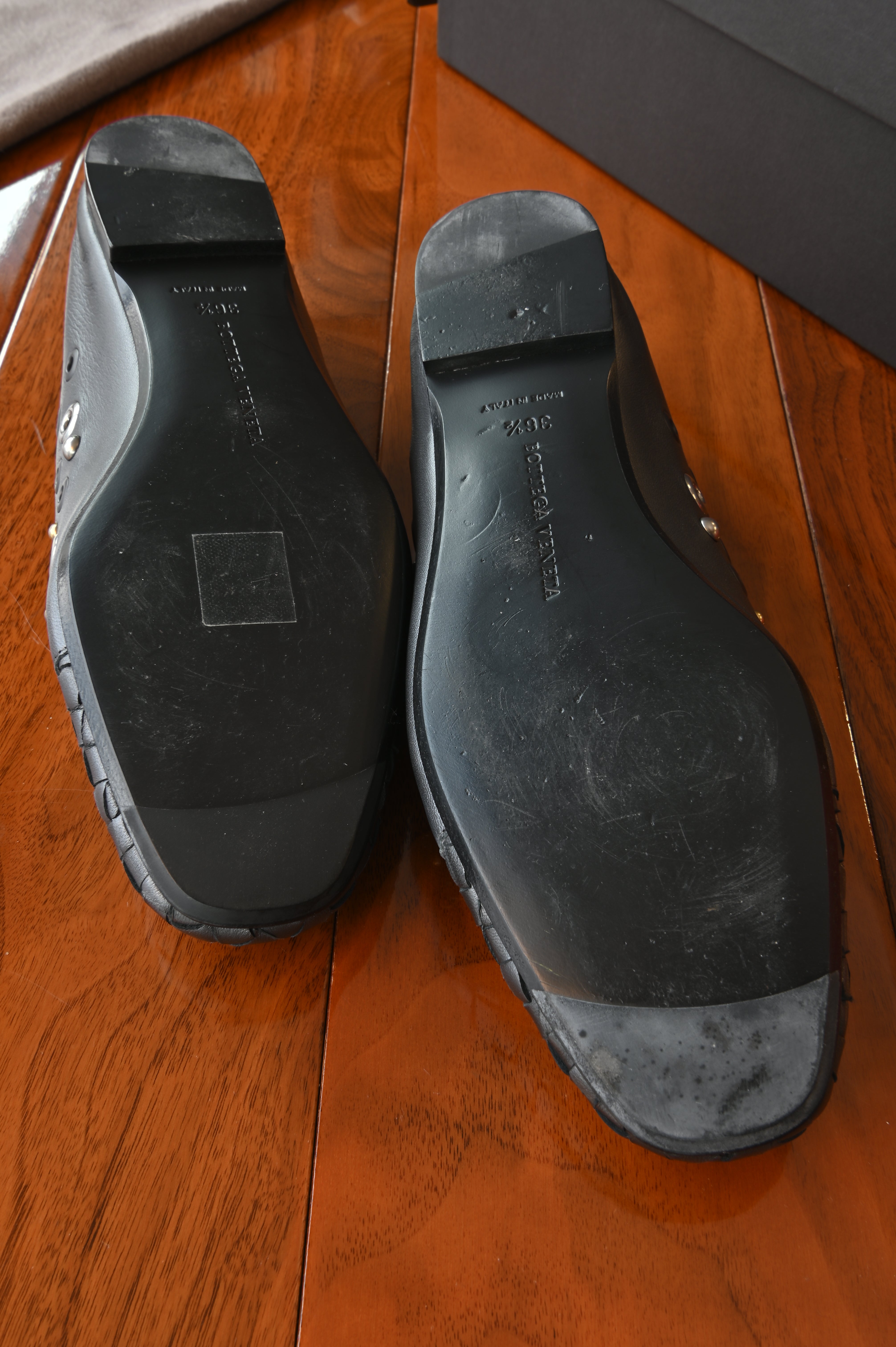 Bottom view of the authentic Bottega Veneta Black Intrecciato Eyelet Leather Loafers highlighting the leather soles, heel condition and size markings.