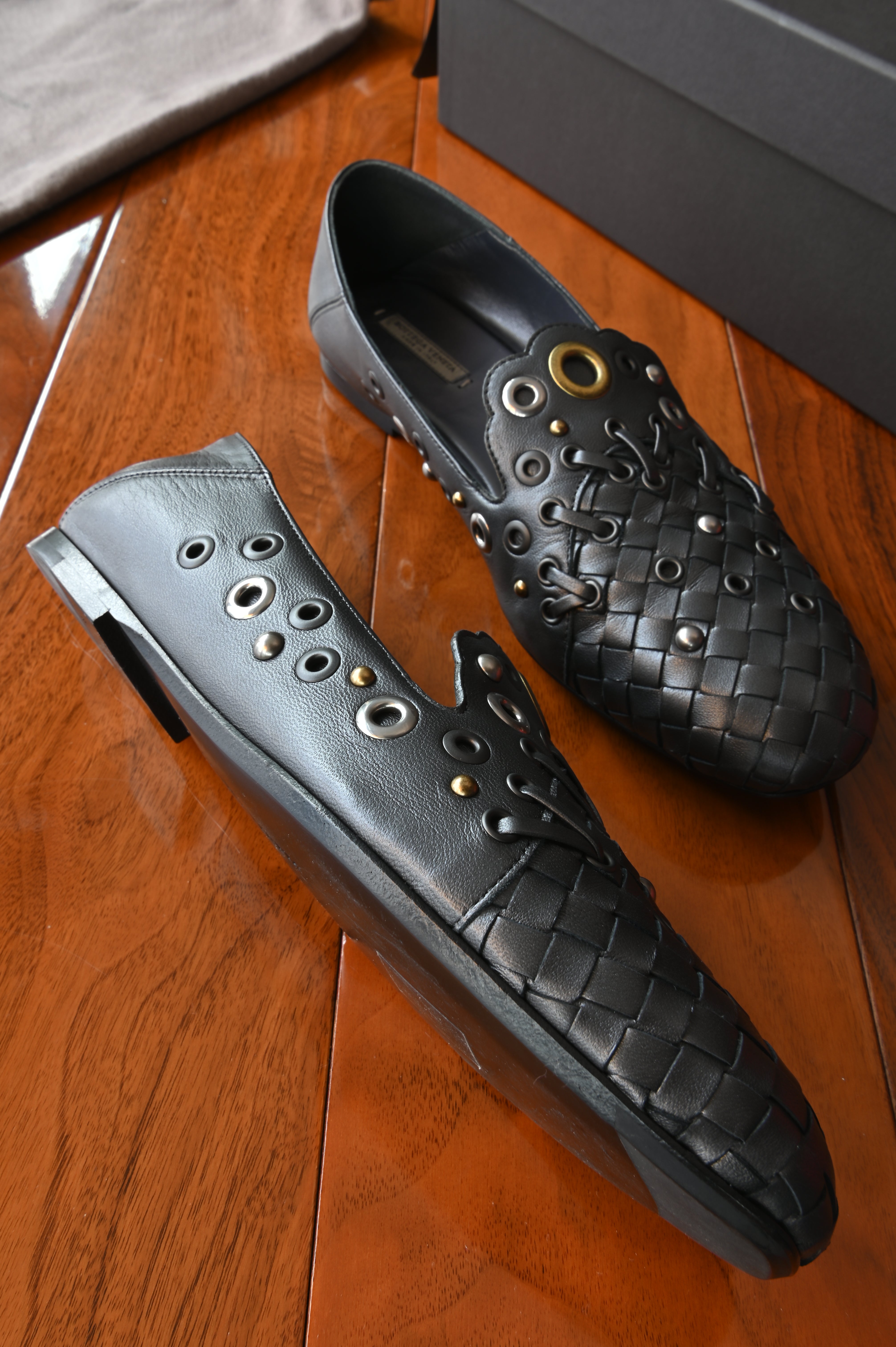 Authentic Bottega Veneta Black Intrecciato Eyelet Leather Loafers showing the left side profile with smooth leather upper, eyelet detailing and woven toe.