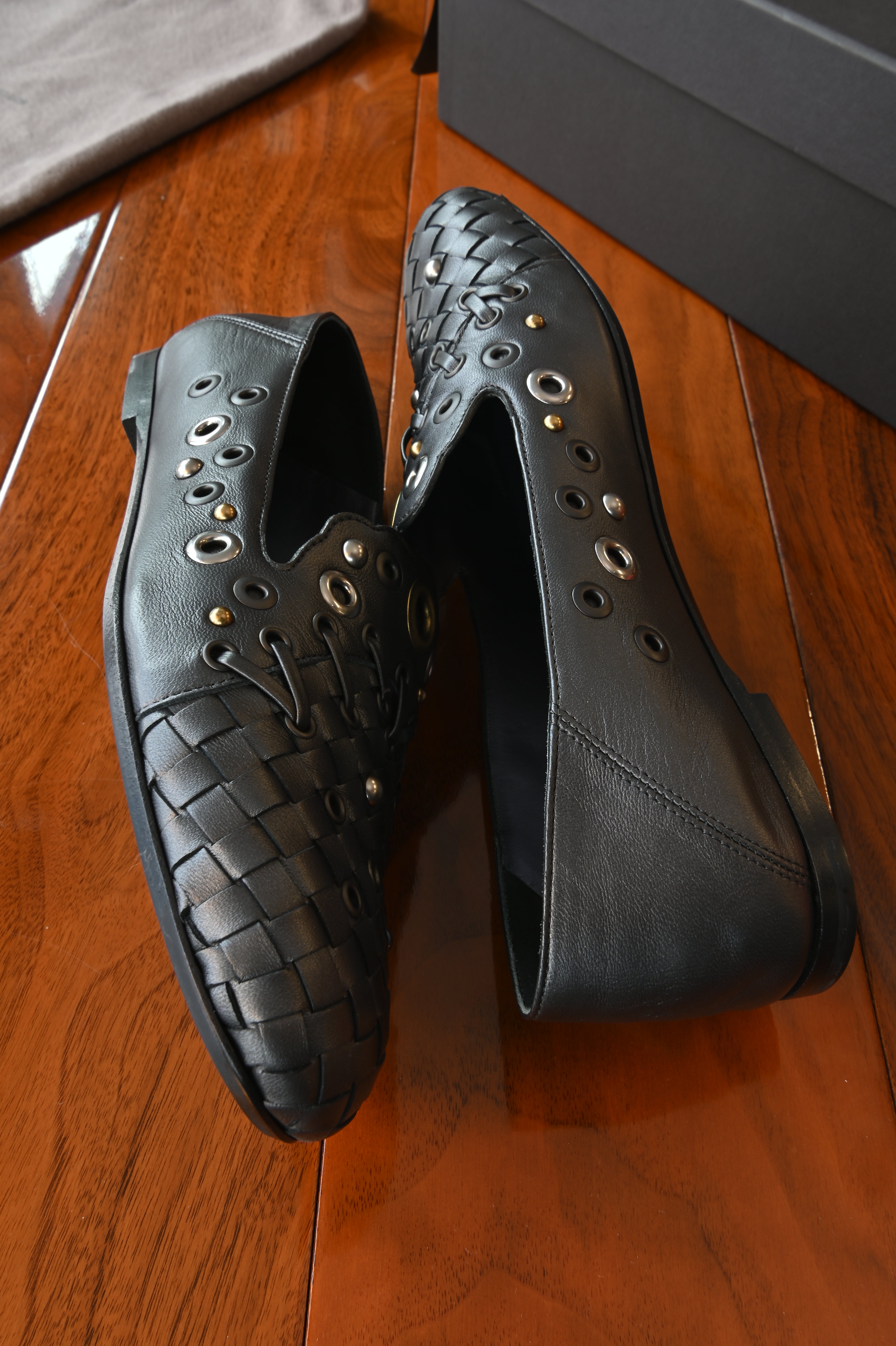 Authentic Bottega Veneta Black Intrecciato Eyelet Leather Loafers displayed from the side, highlighting the smooth leather construction and eyelet embellishments.
