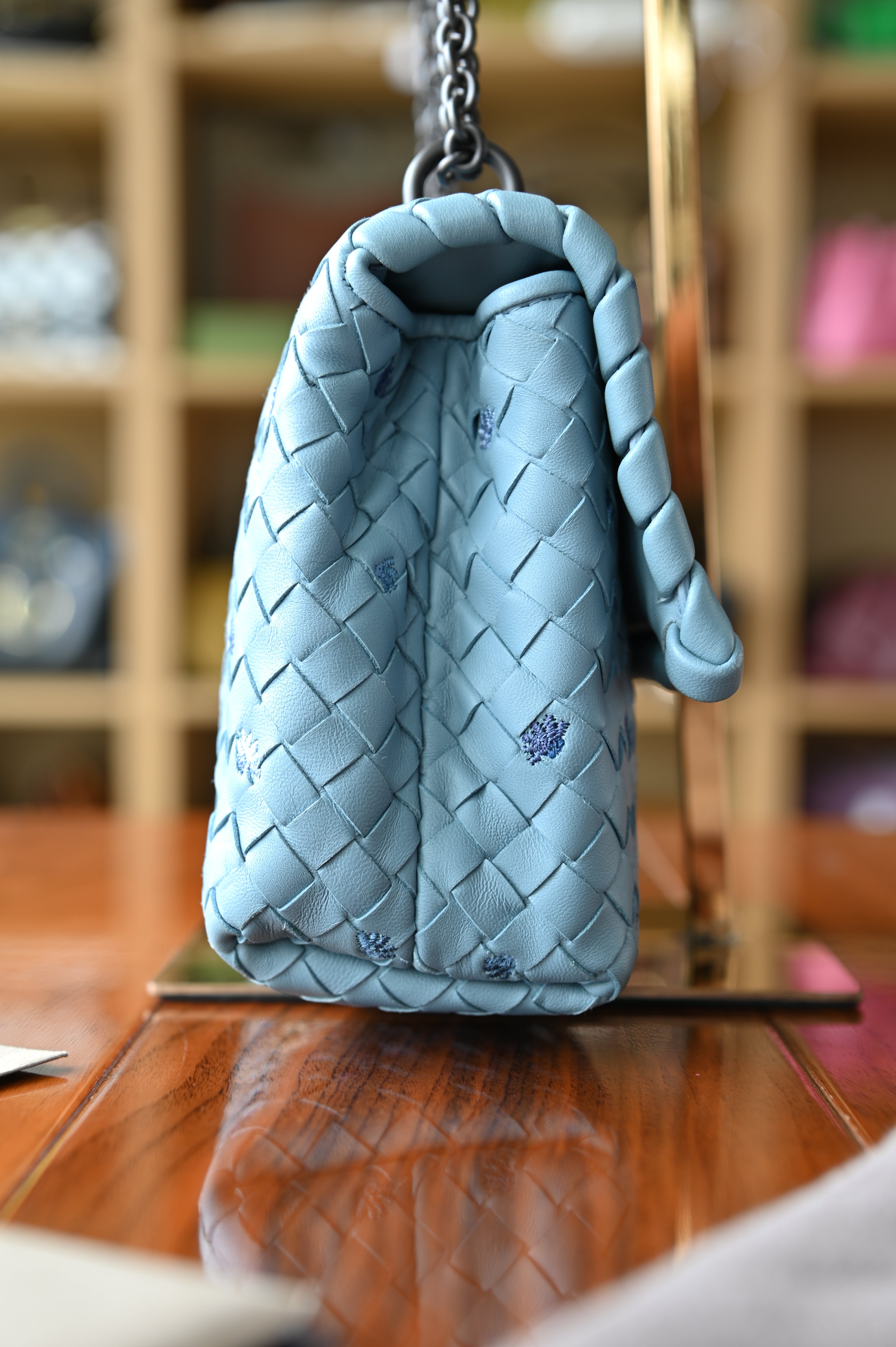 Authentic Bottega Veneta Blue Intrecciato Woven Crossbody Bag showing the left side profile with woven leather body and chain shoulder strap.