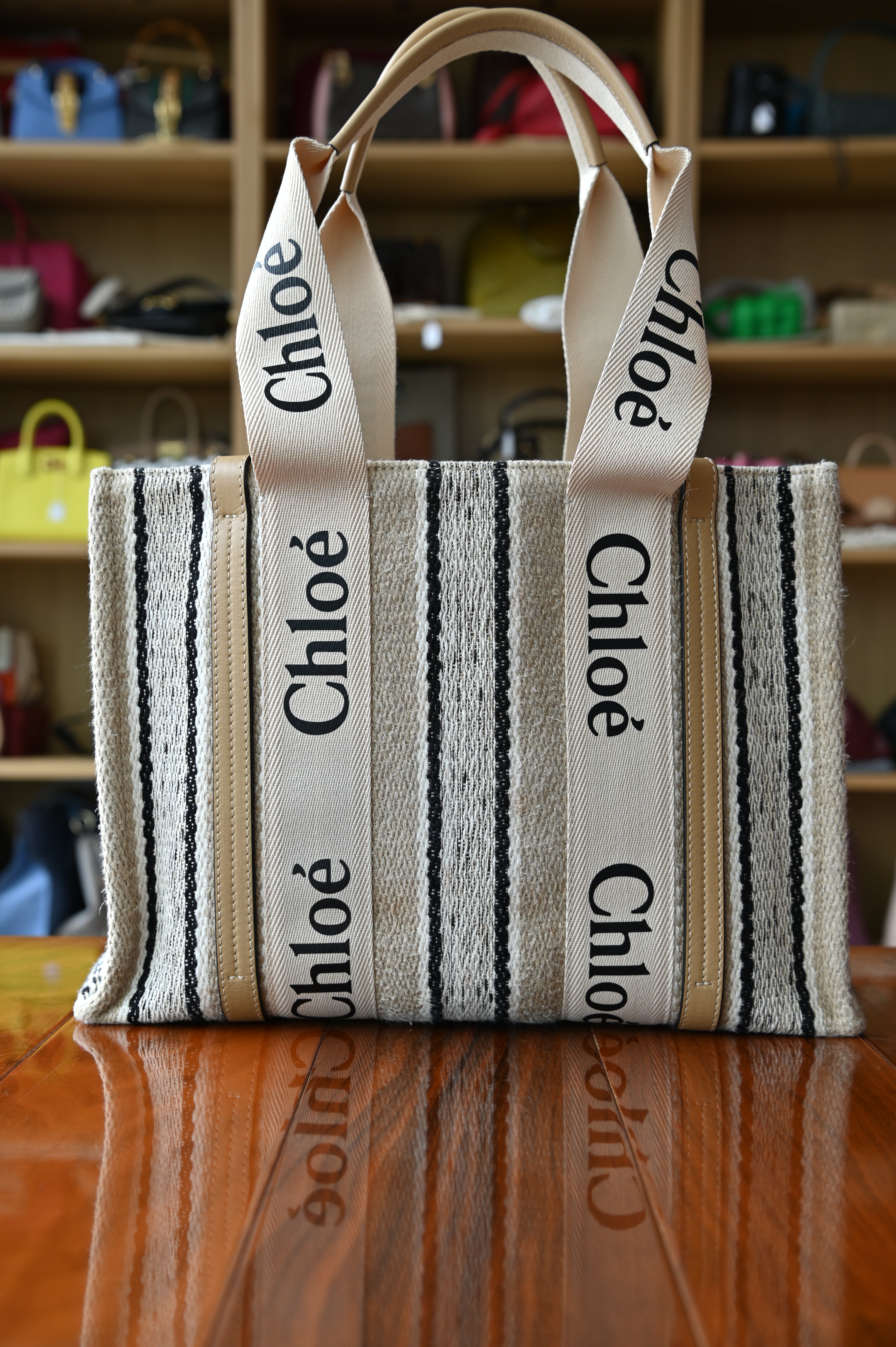 Authentic Chloé Woody Medium Striped Tote Bag shown from a front angled view highlighting the signature logo webbing and structured canvas body.