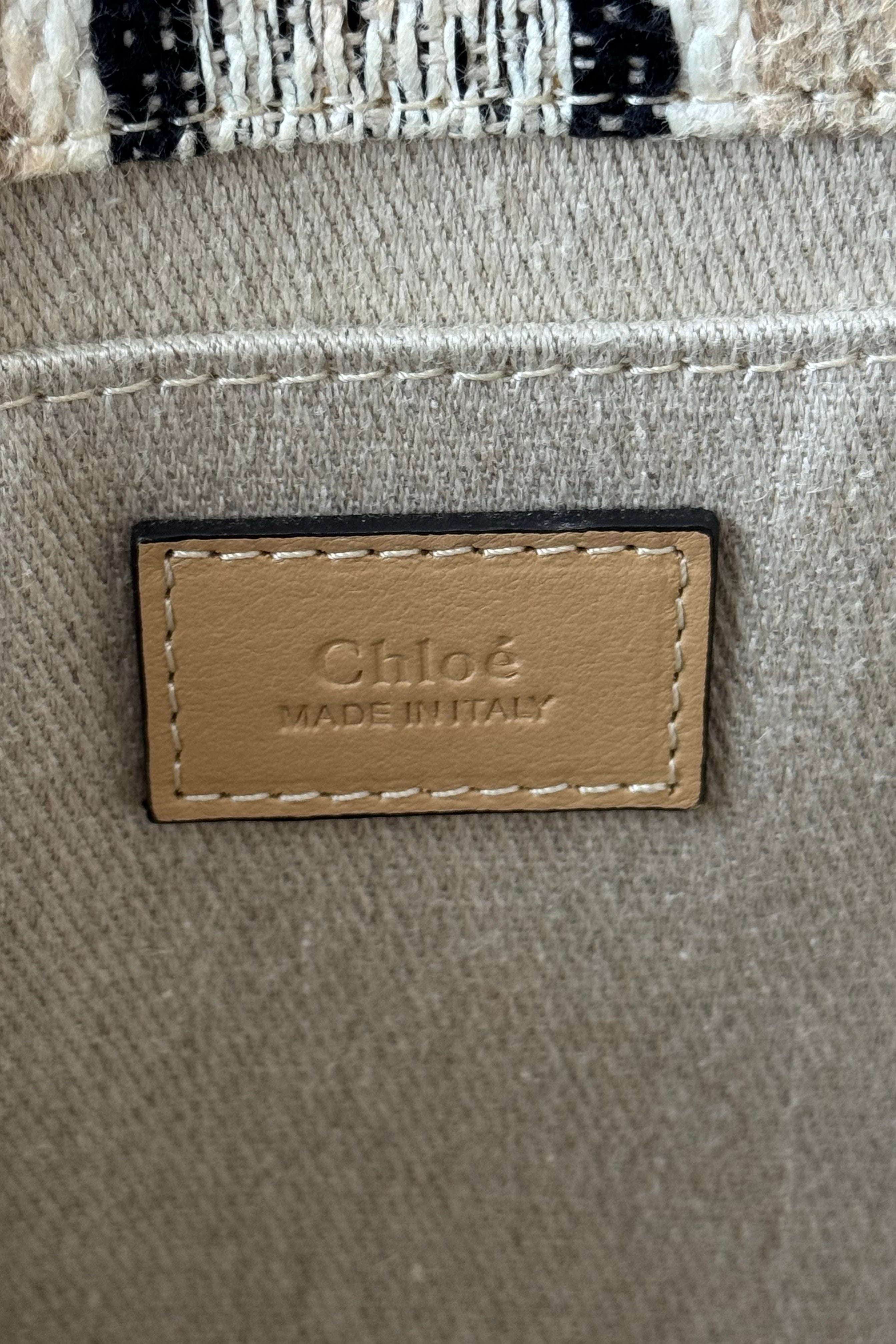 Close-up of the authentic Chloé Woody Medium Striped Tote Bag interior leather logo patch showcasing premium craftsmanship.