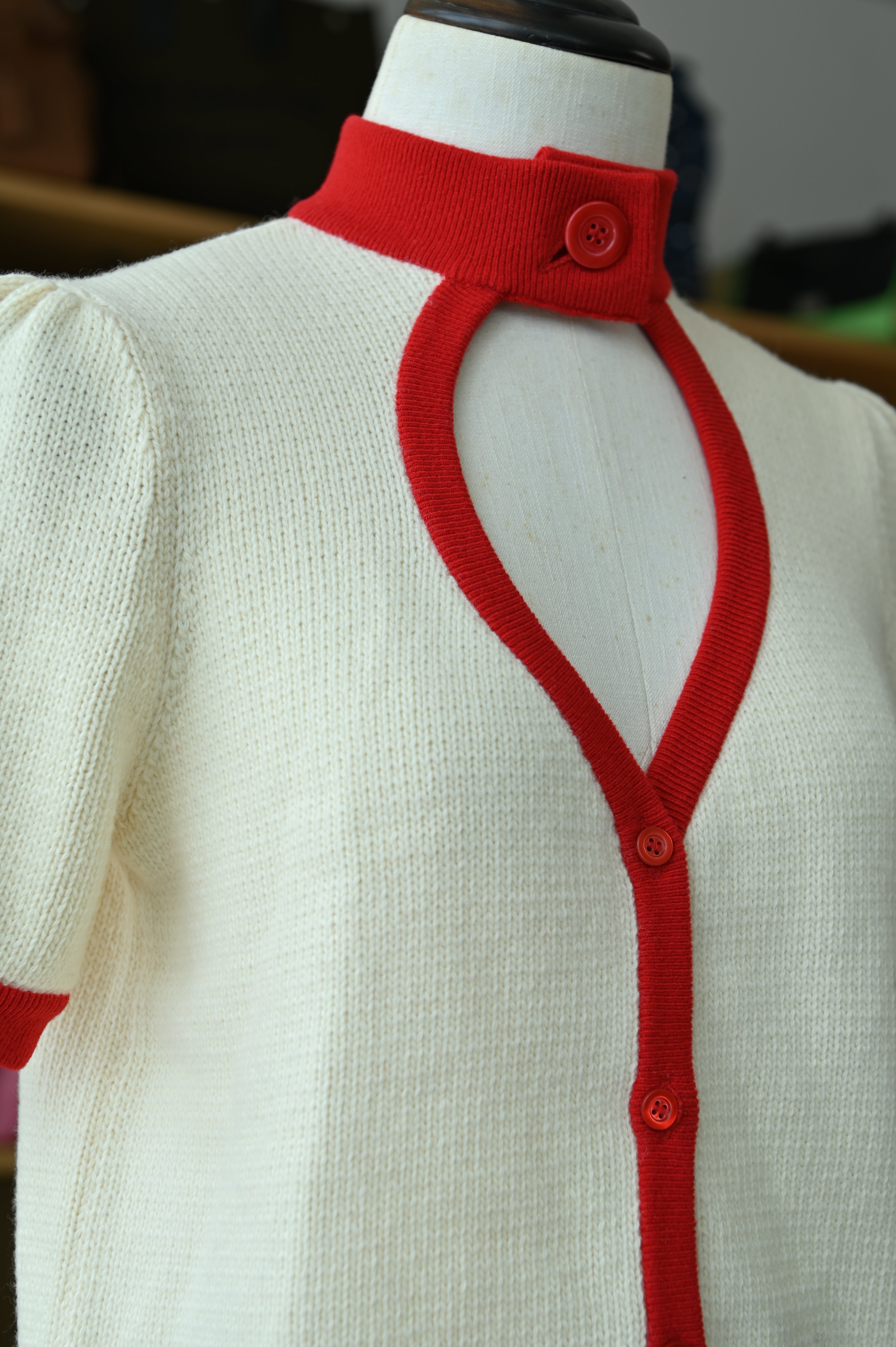 Close-up of the authentic Christian Dior White & Red Knit Cardigan highlighting the sleeve, cuff and contrast red trim.
