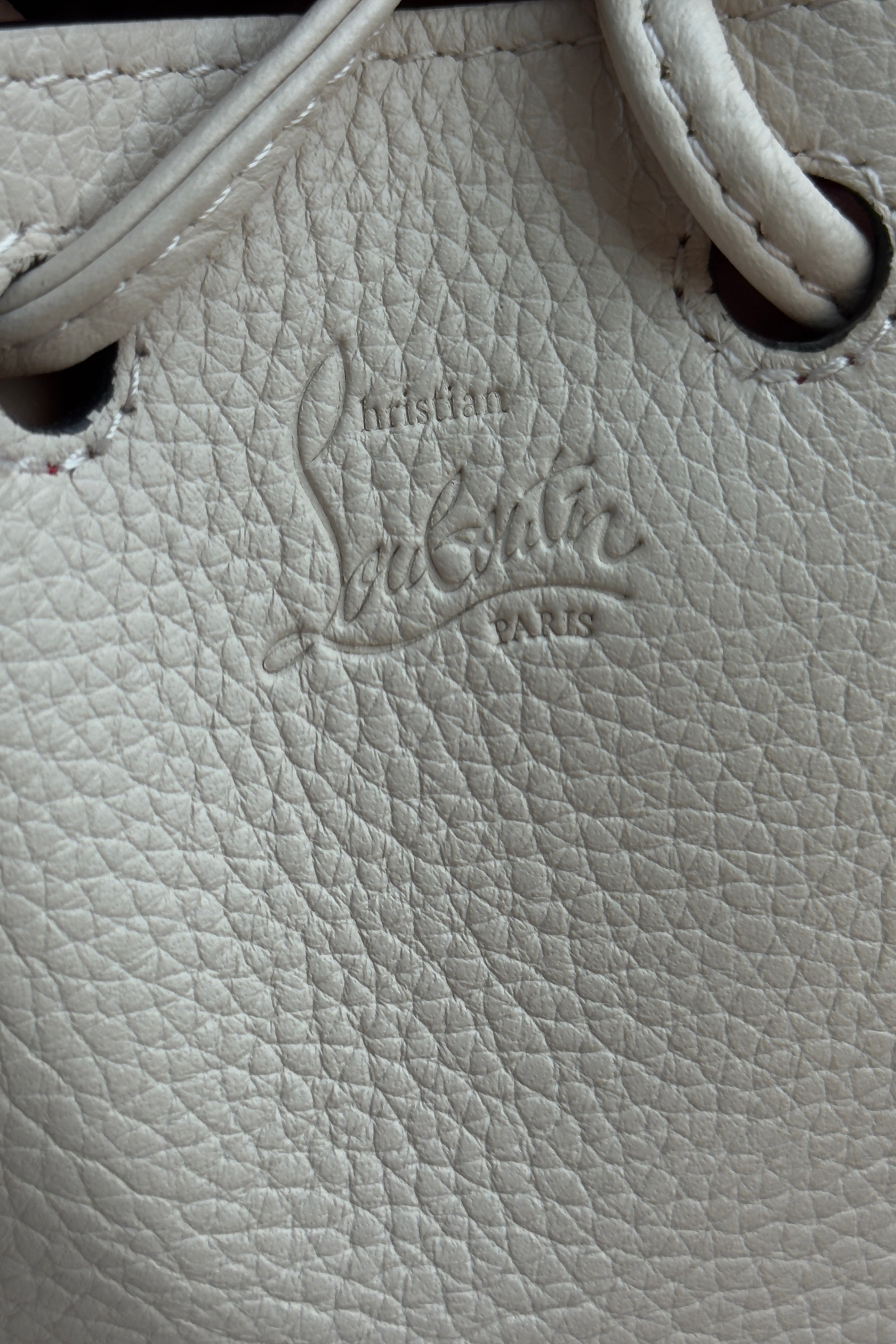 Close-up of the authentic Christian Louboutin By My Side Bucket Bag showing grained calf leather and embossed branding.