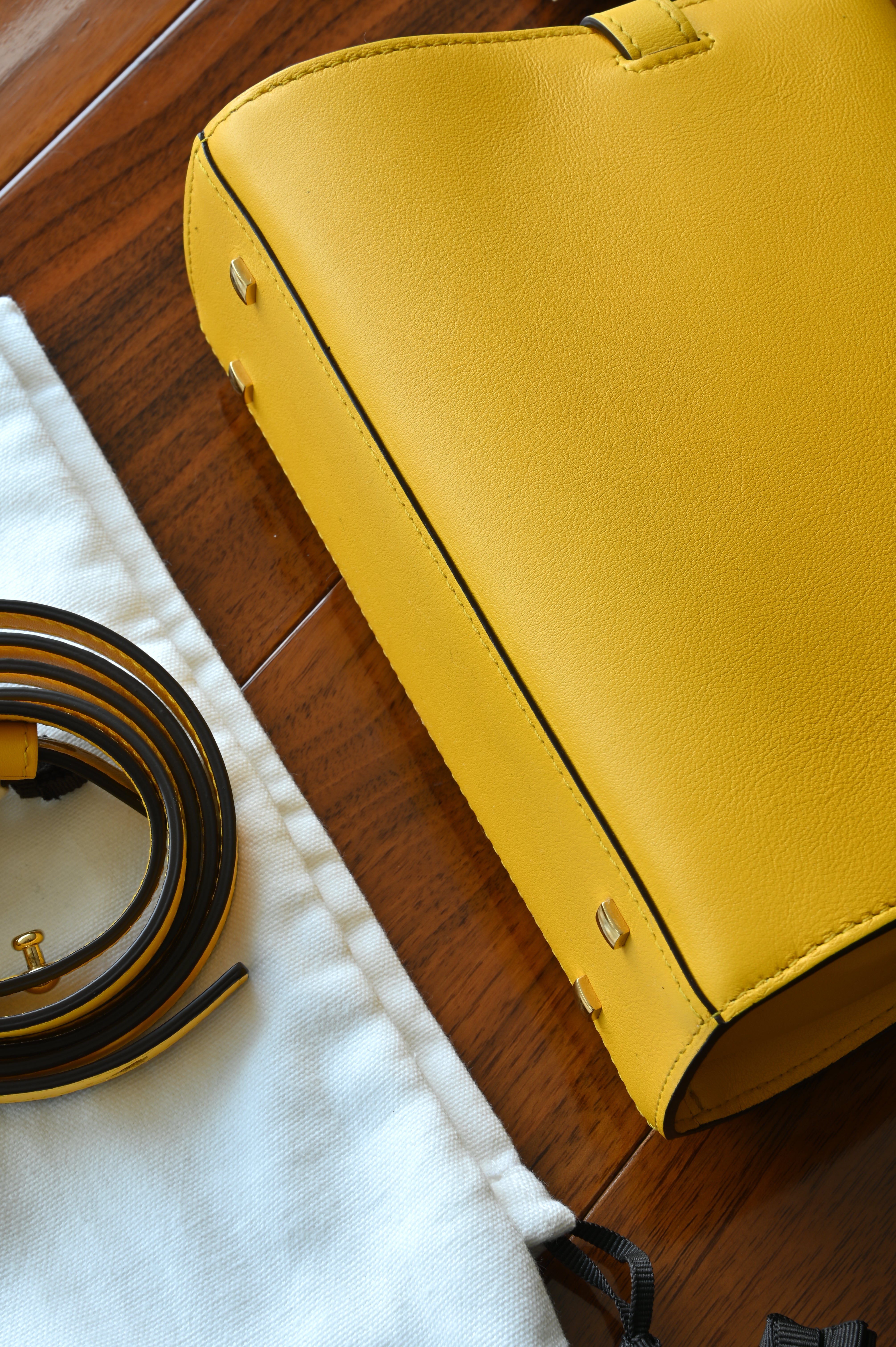 Close-up of the authentic Delvaux Tempête Mini Souple Safra Yellow Leather Top Handle Bag base showcasing the smooth leather finish and meticulous stitching.