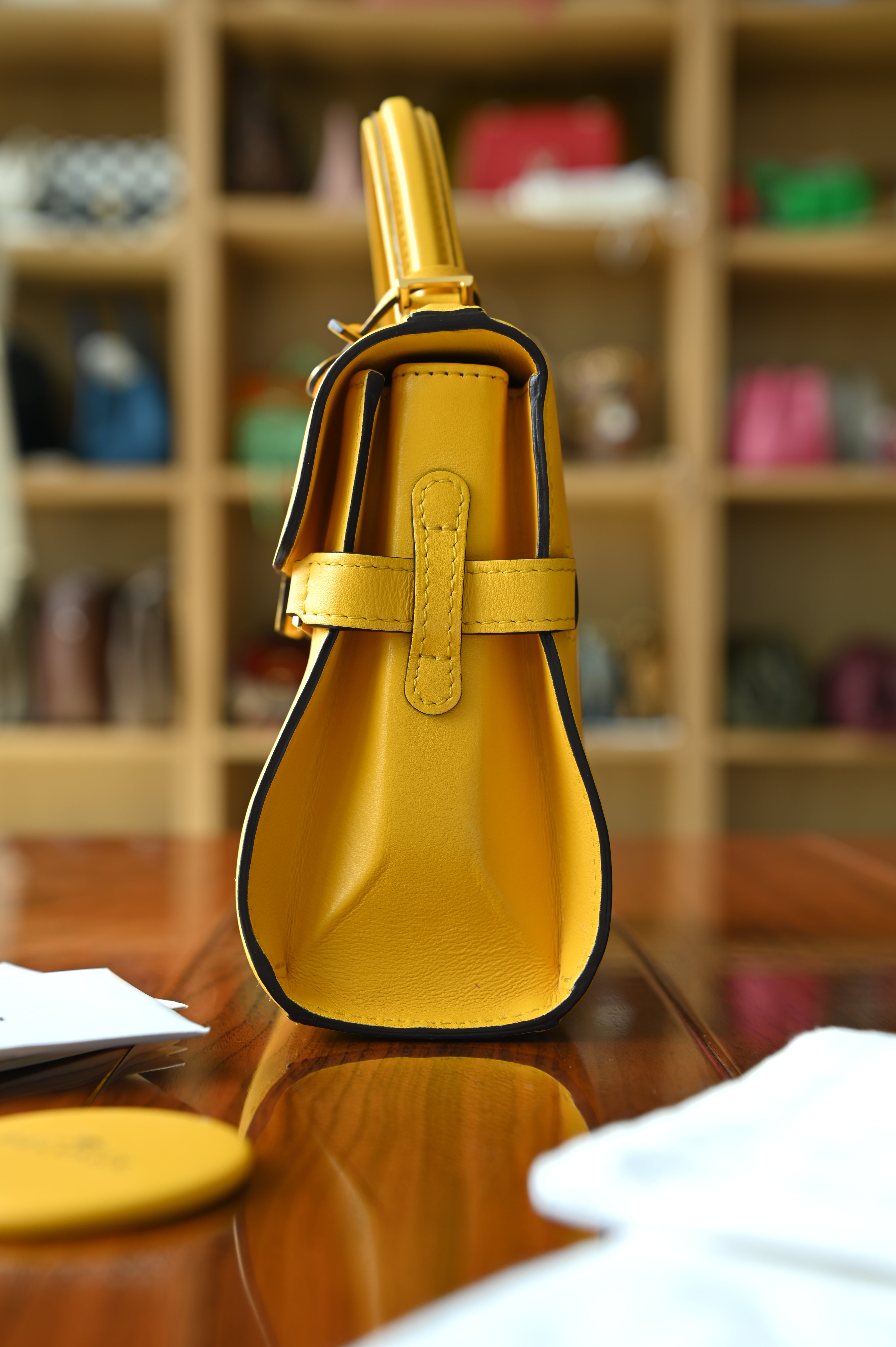 Authentic Delvaux Tempête Mini Souple Safra Yellow Leather Top Handle Bag showing the right side profile with signature structured design and leather craftsmanship.