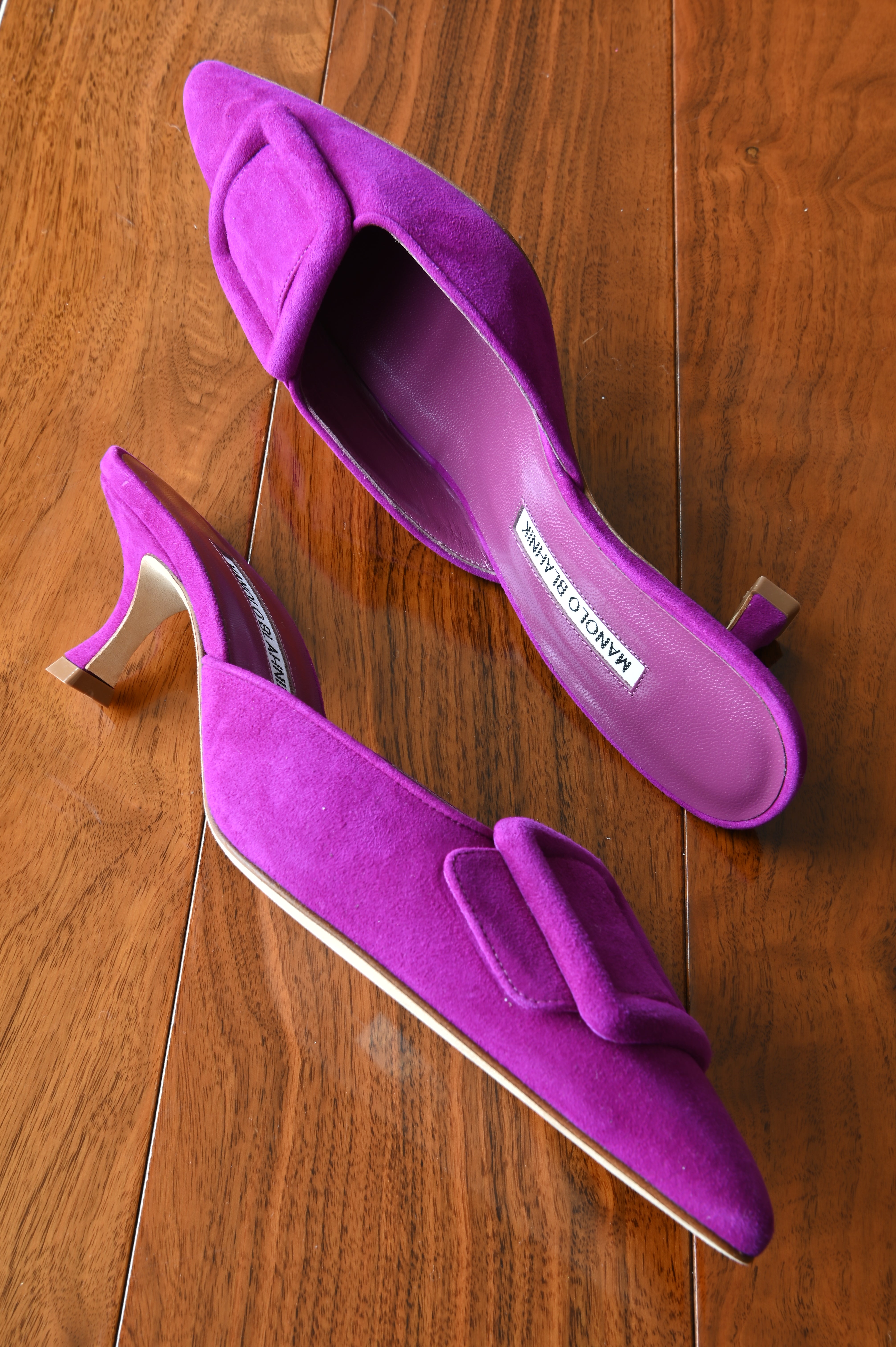 Top view of authentic Manolo Blahnik purple suede buckle mules featuring the leather footbeds and signature oversized suede buckle