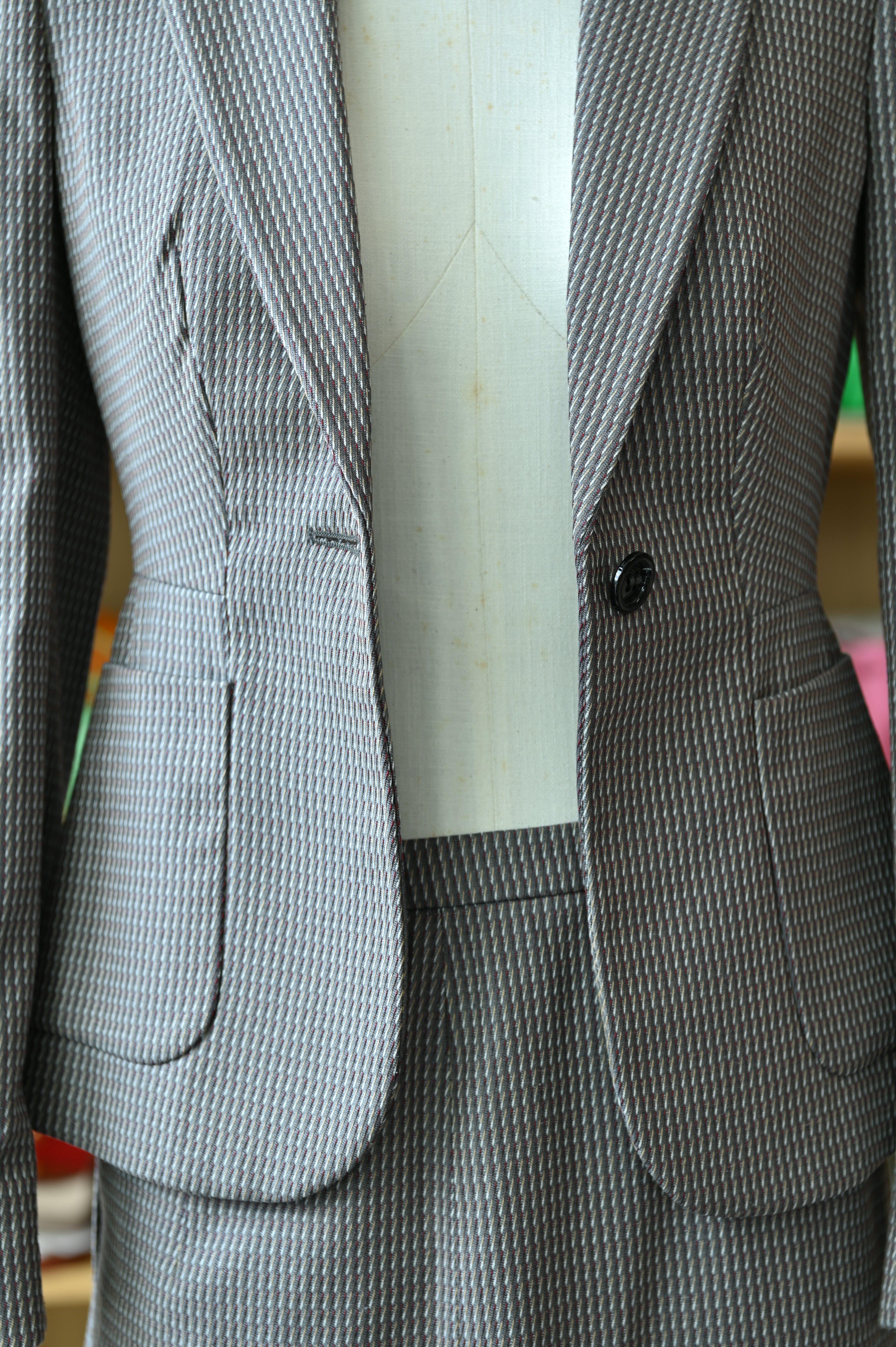 Close-up of the authentic Miu Miu Grey Checked Two-Piece Skirt Suit featuring the blazer pocket, button closure and checked pattern.