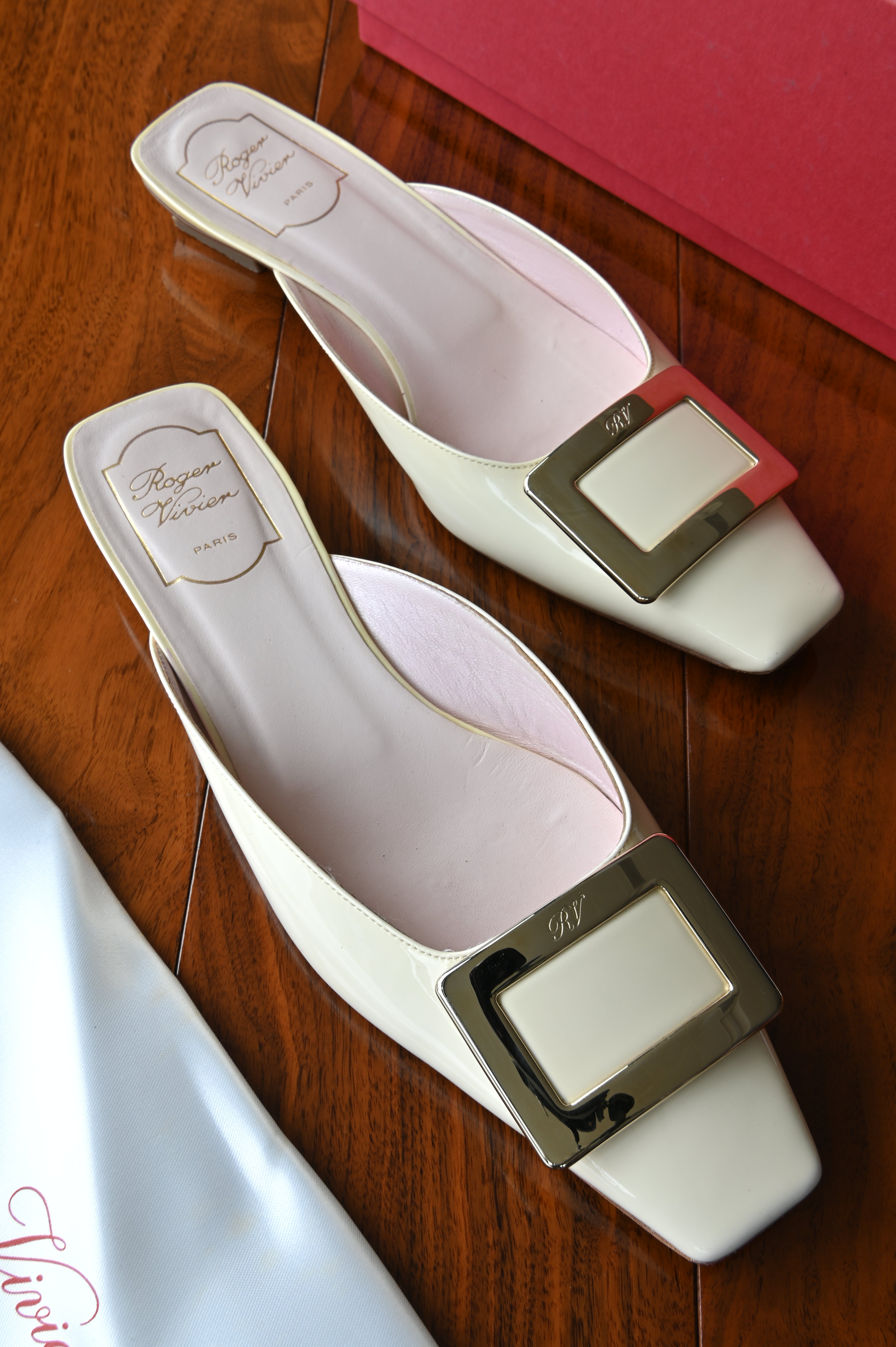 Authentic Roger Vivier Belle Vivier ivory patent leather mules featuring the signature oversized metal buckle, square toe, and elegant low block heel.