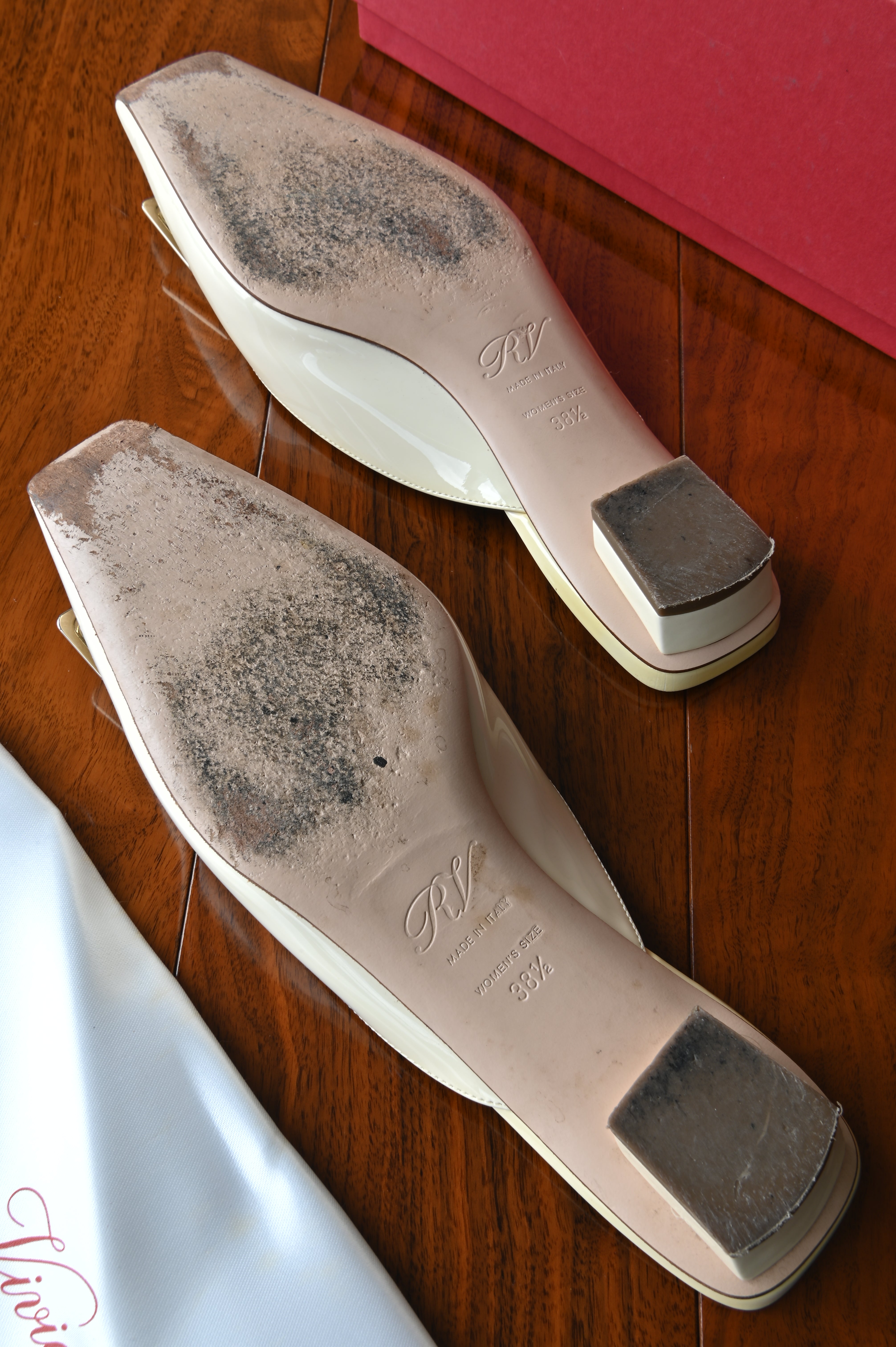 Bottom view of authentic Roger Vivier Belle Vivier ivory patent leather mules showing light wear on the leather outsoles consistent with careful use.