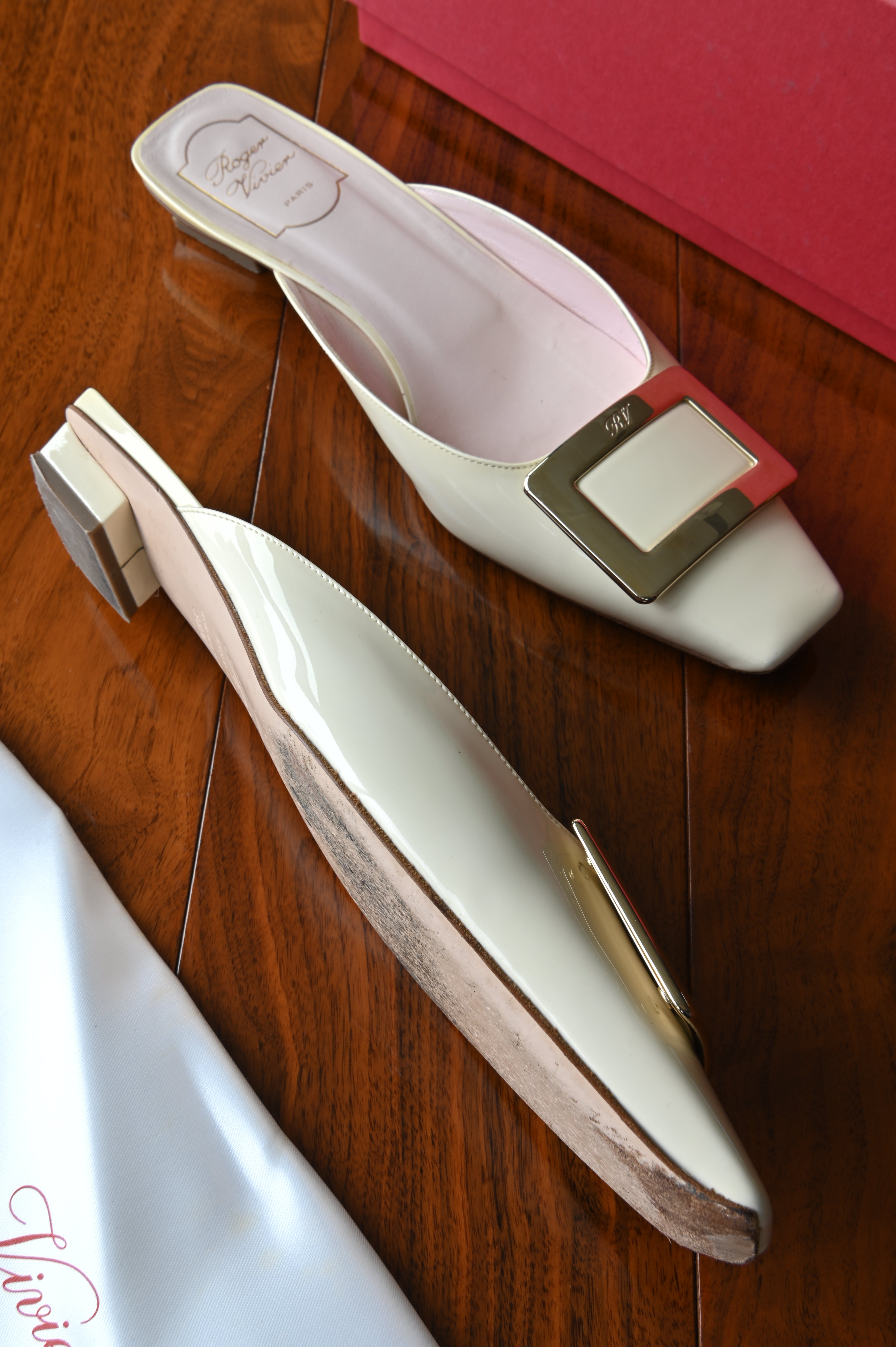 Side profile of authentic Roger Vivier Belle Vivier ivory patent leather mules highlighting the glossy patent leather and low block heel.