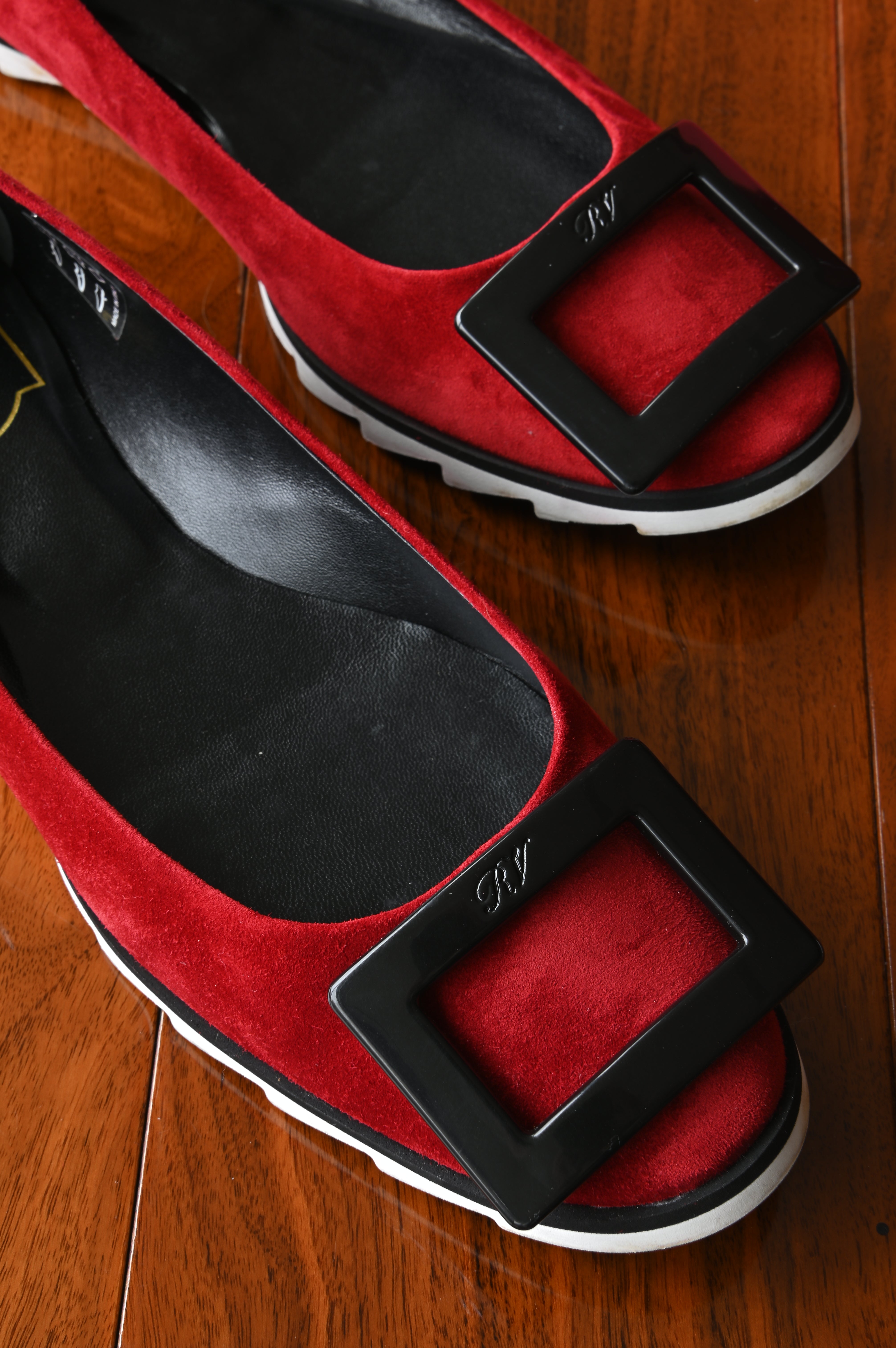 Close-up of the iconic oversized black Roger Vivier buckle set against rich red suede.