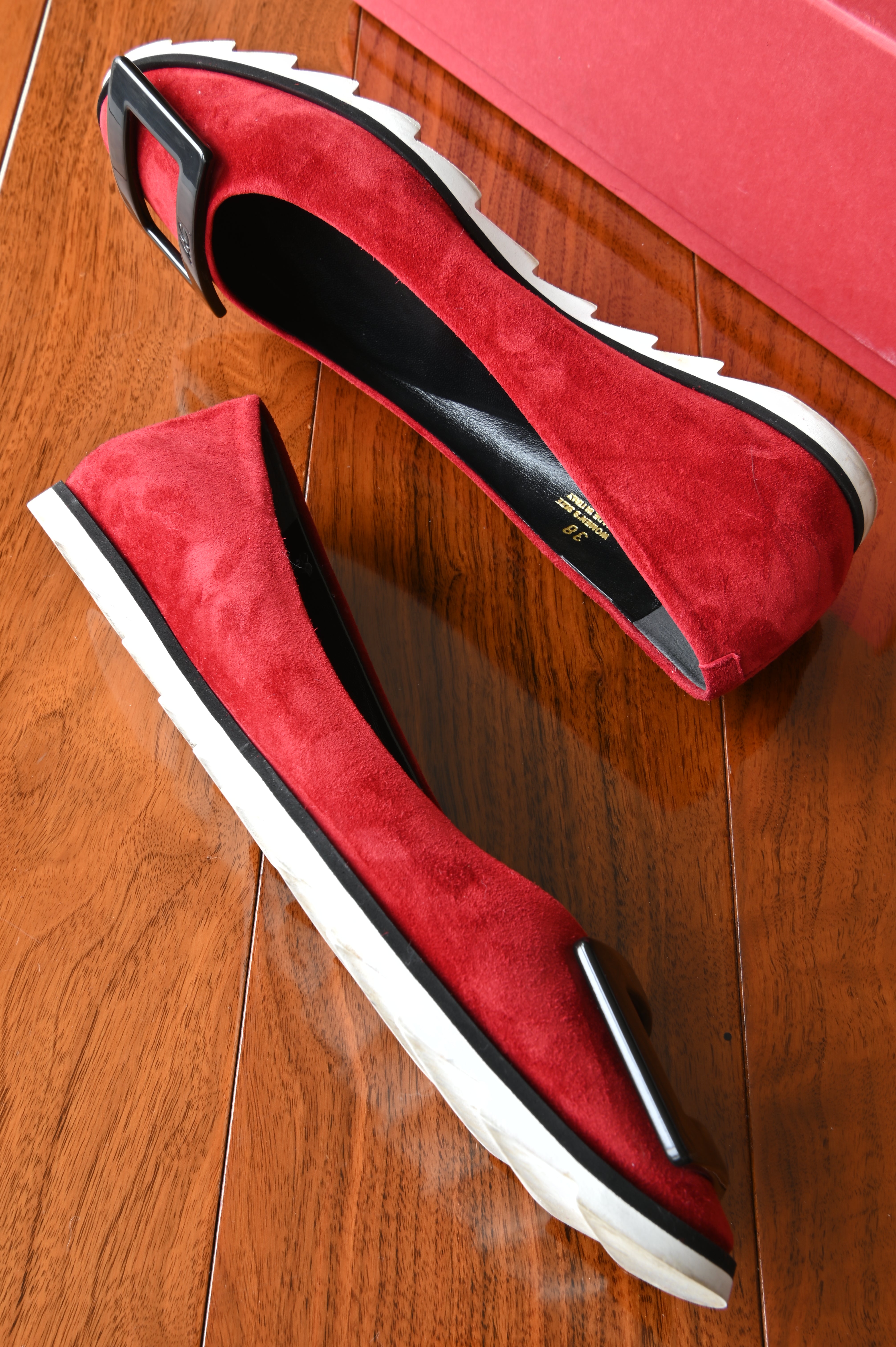 Side profile of authentic Roger Vivier Gommettine ballet flats highlighting the rich red suede upper and lightweight white serrated rubber sole.