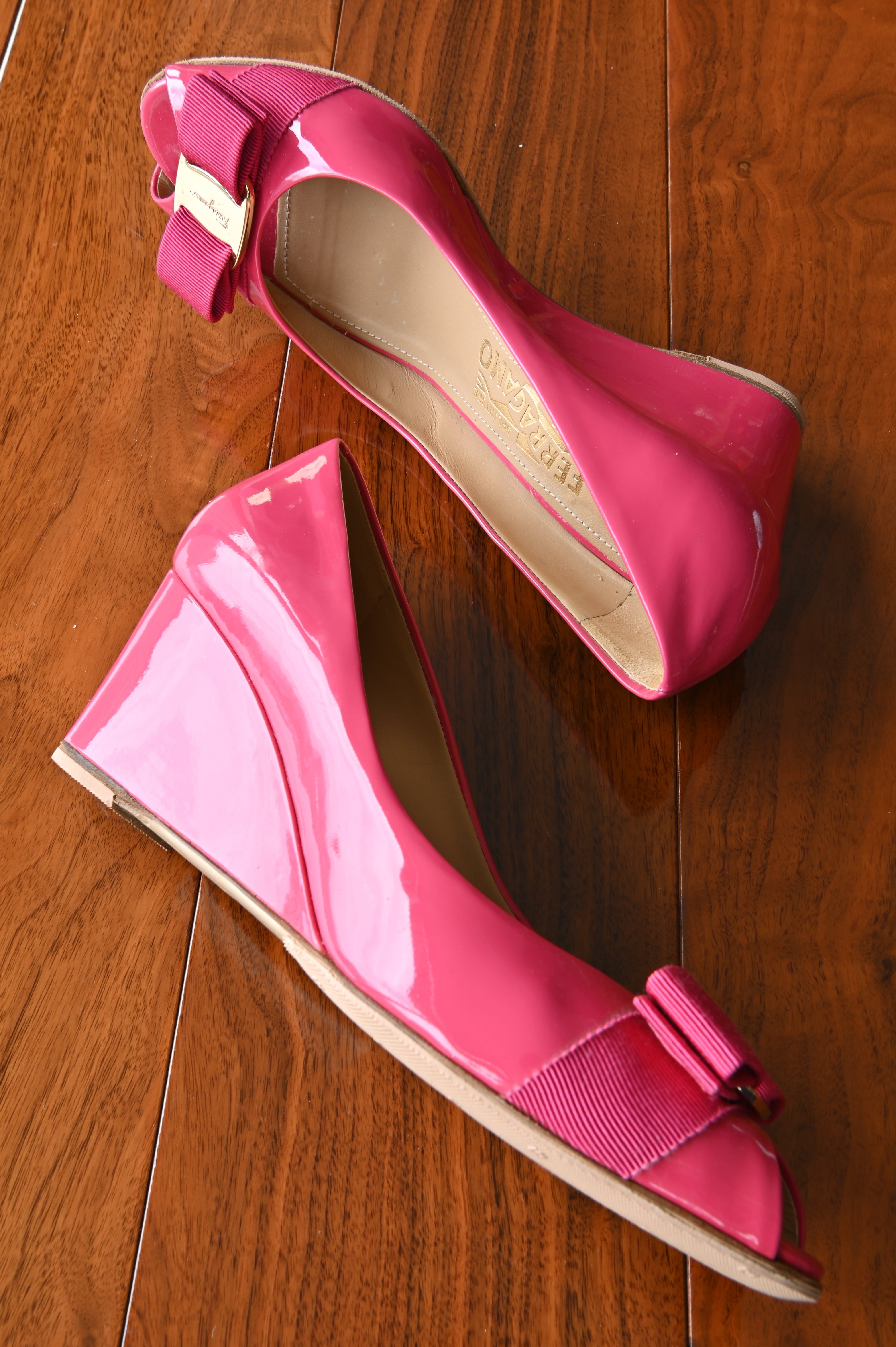 Top view of authentic Salvatore Ferragamo pink patent leather Vara Bow Wedge Pumps featuring the beige leather lining and signature Vara grosgrain bow with gold-tone logo plaque.