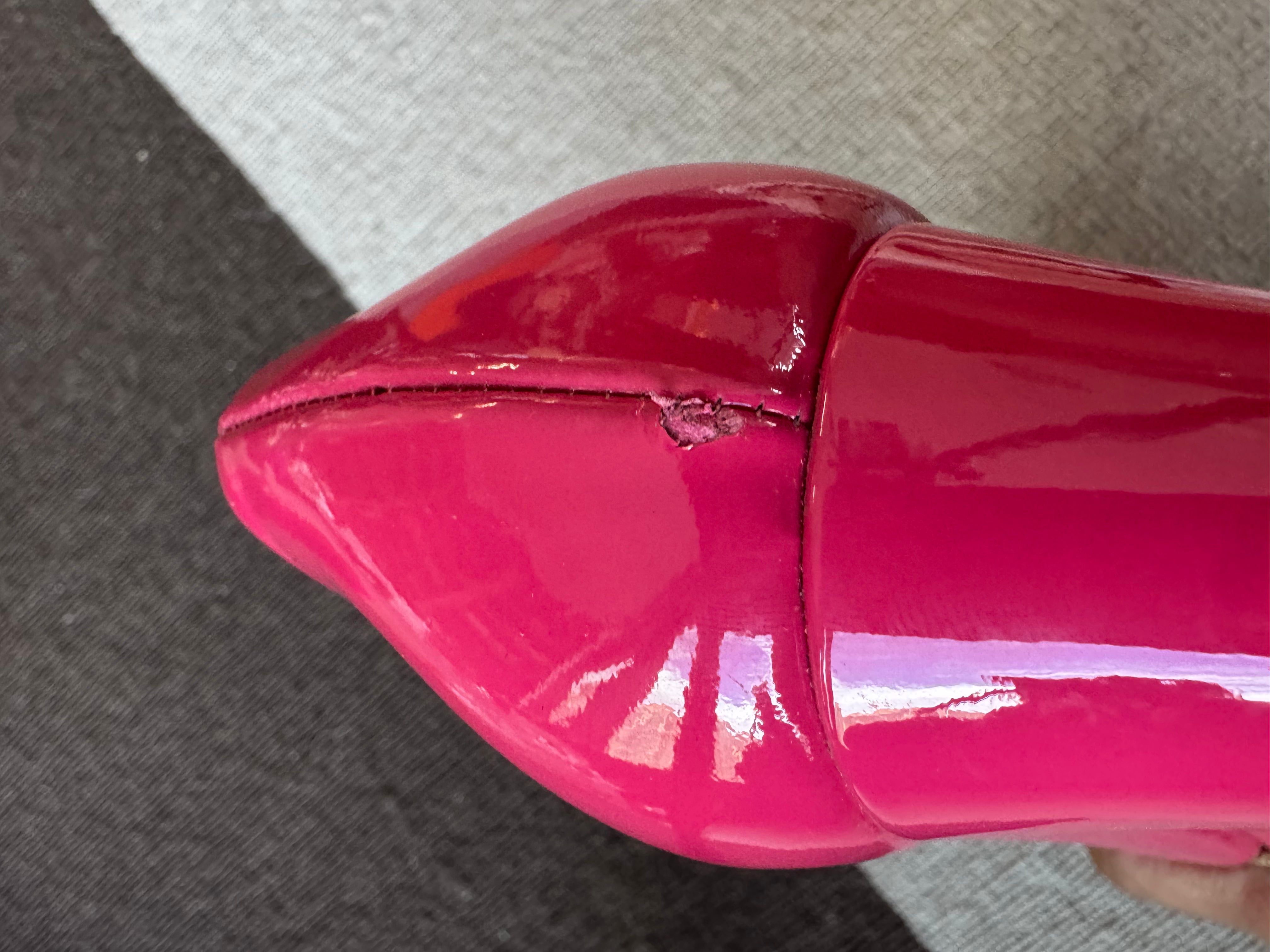 Close-up showing the small chip on the left shoe’s patent leather upper of the authentic Salvatore Ferragamo pink patent leather Vara Bow Wedge Pumps.