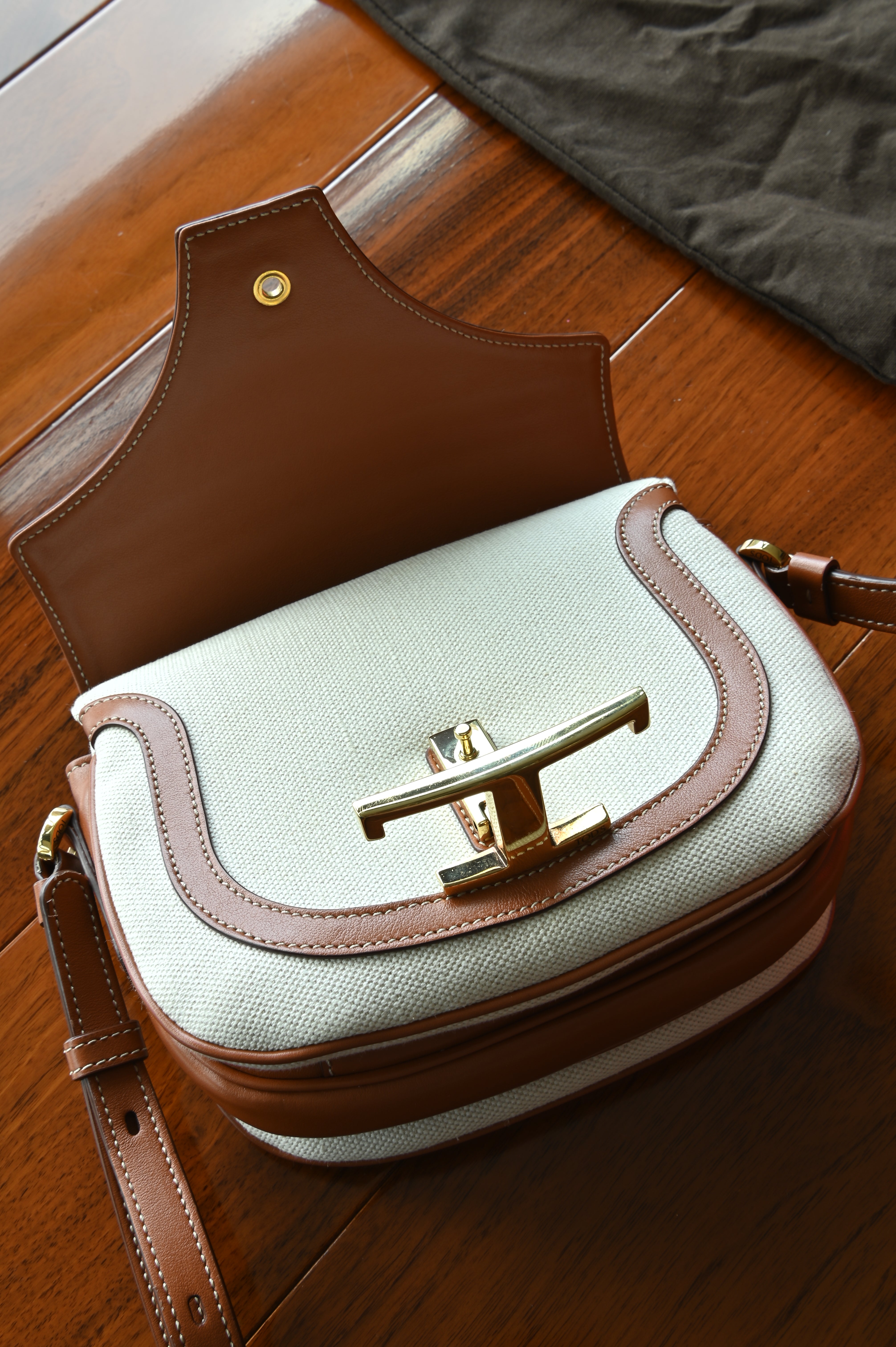 Close-up of the authentic Tod’s Brown & Beige Canvas Logo Crossbody Bag highlighting the signature logo hardware and flap closure.