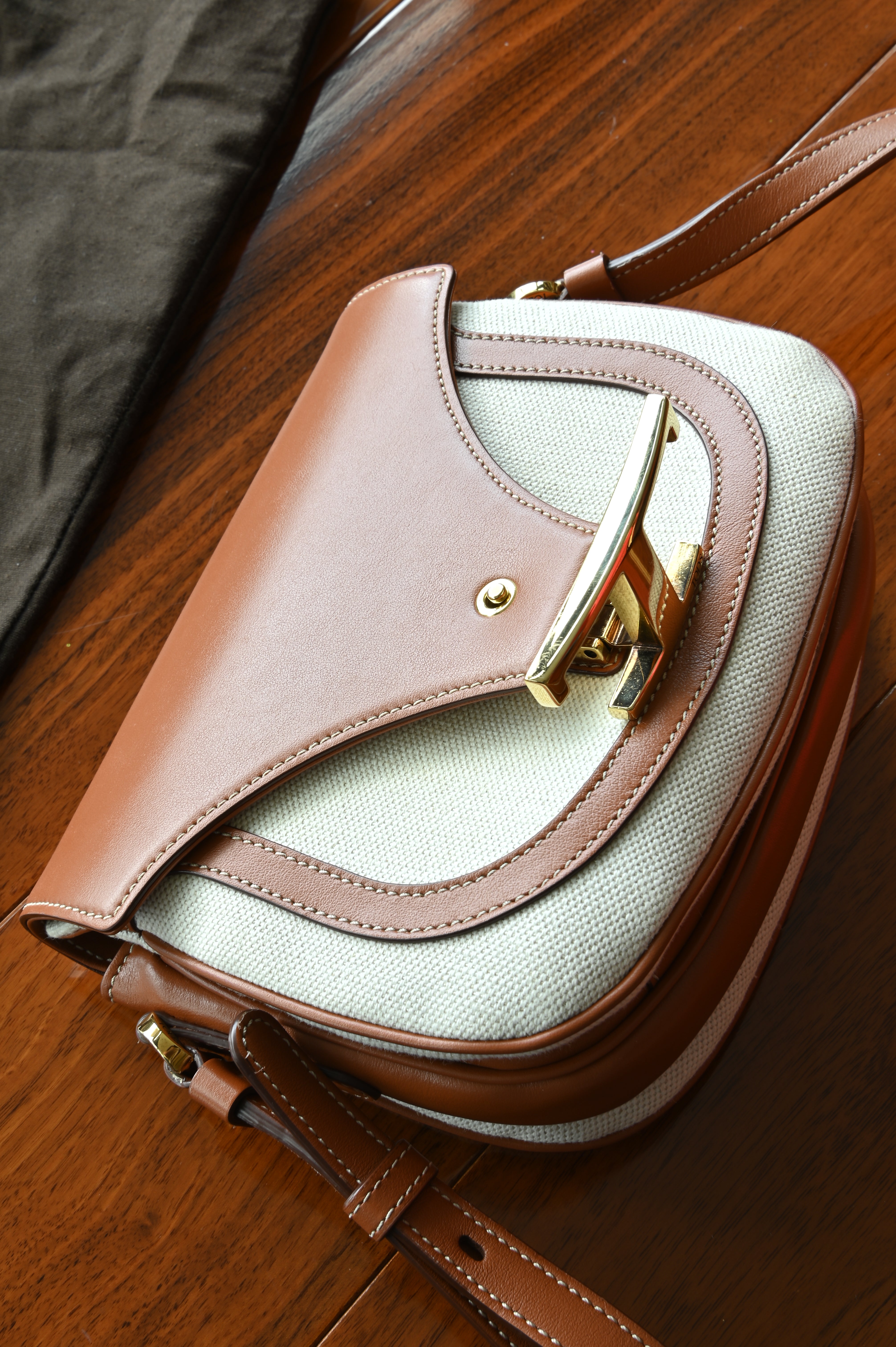 Authentic Tod’s Brown & Beige Canvas Logo Crossbody Bag displayed from an angled front view, showcasing the signature logo hardware and leather trim.
