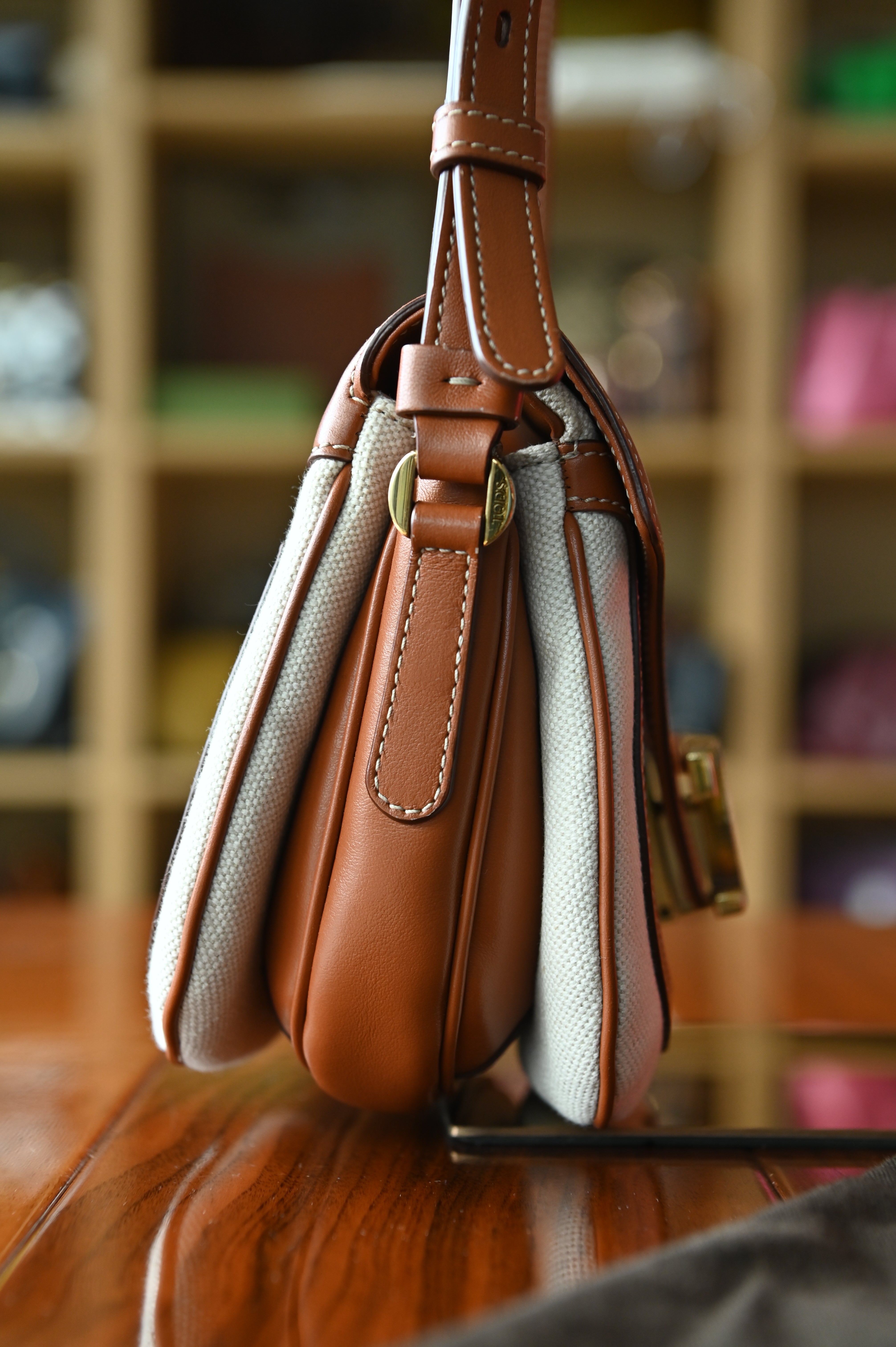 Authentic Tod’s Brown & Beige Canvas Logo Crossbody Bag showing the left side profile with structured canvas body and leather trim.
