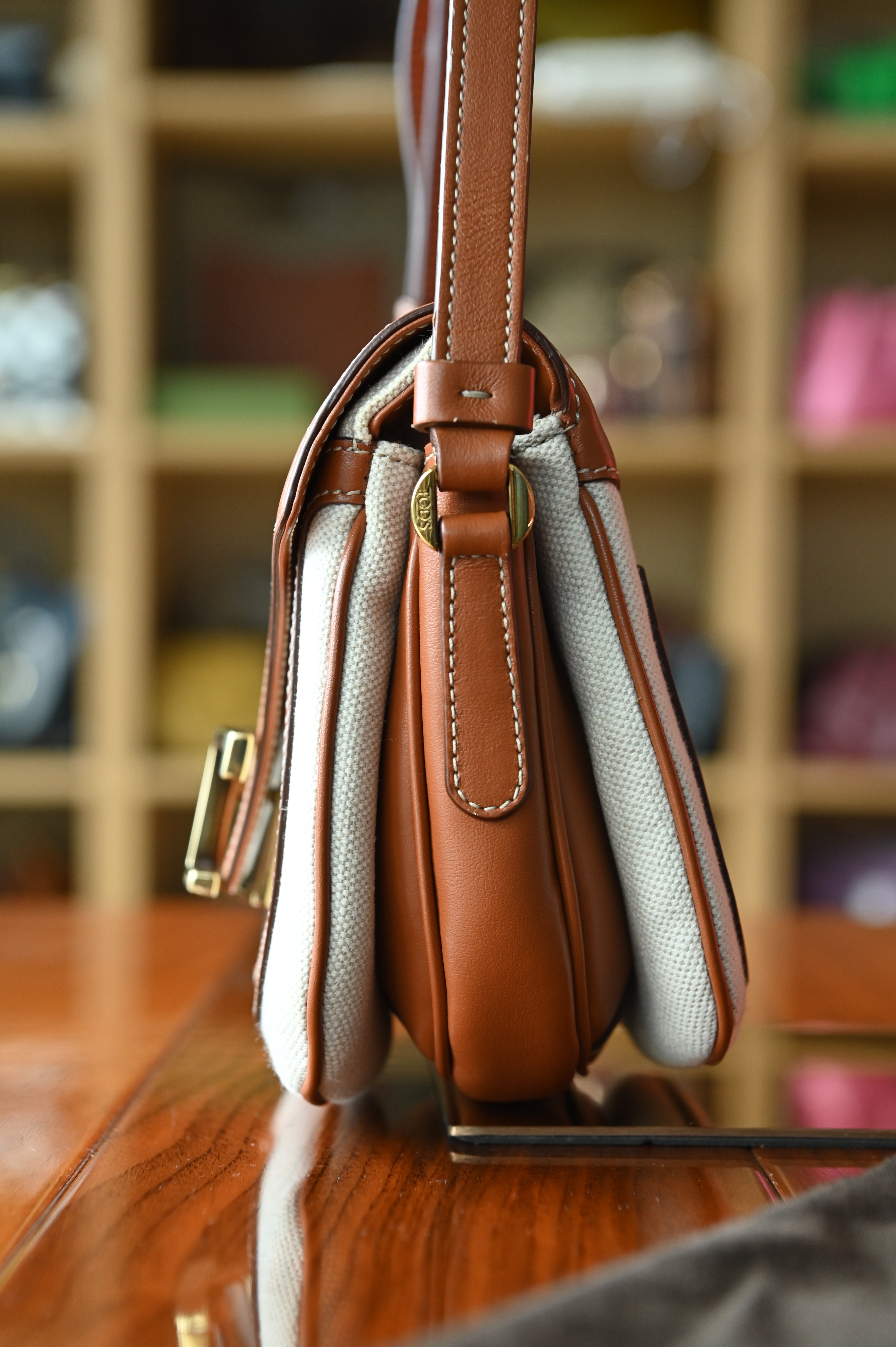 Authentic Tod’s Brown & Beige Canvas Logo Crossbody Bag showing the right side profile with adjustable leather shoulder strap and structured silhouette.