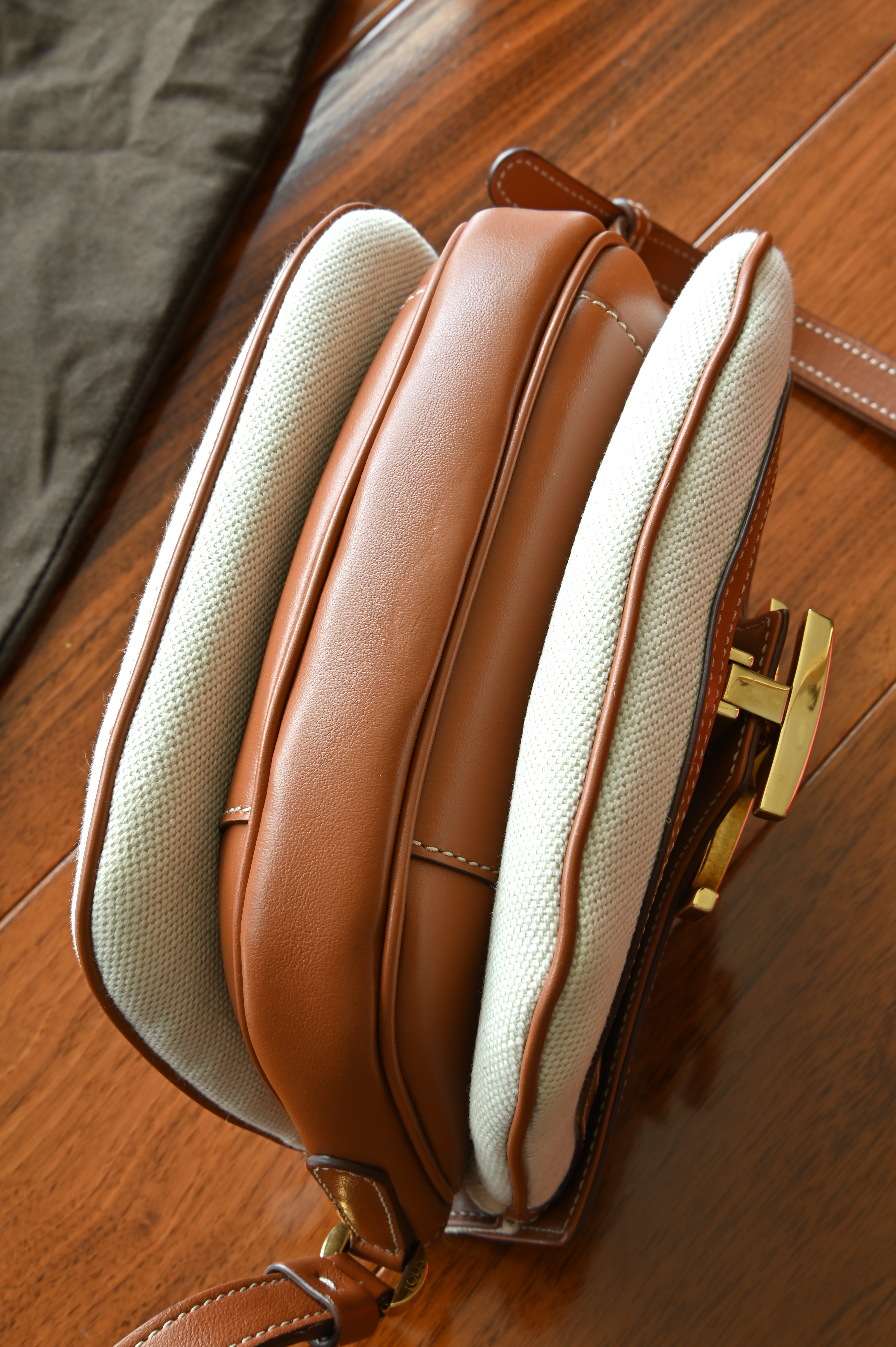 Authentic Tod’s Brown & Beige Canvas Logo Crossbody Bag viewed from above, highlighting the adjustable leather strap and flap closure.
