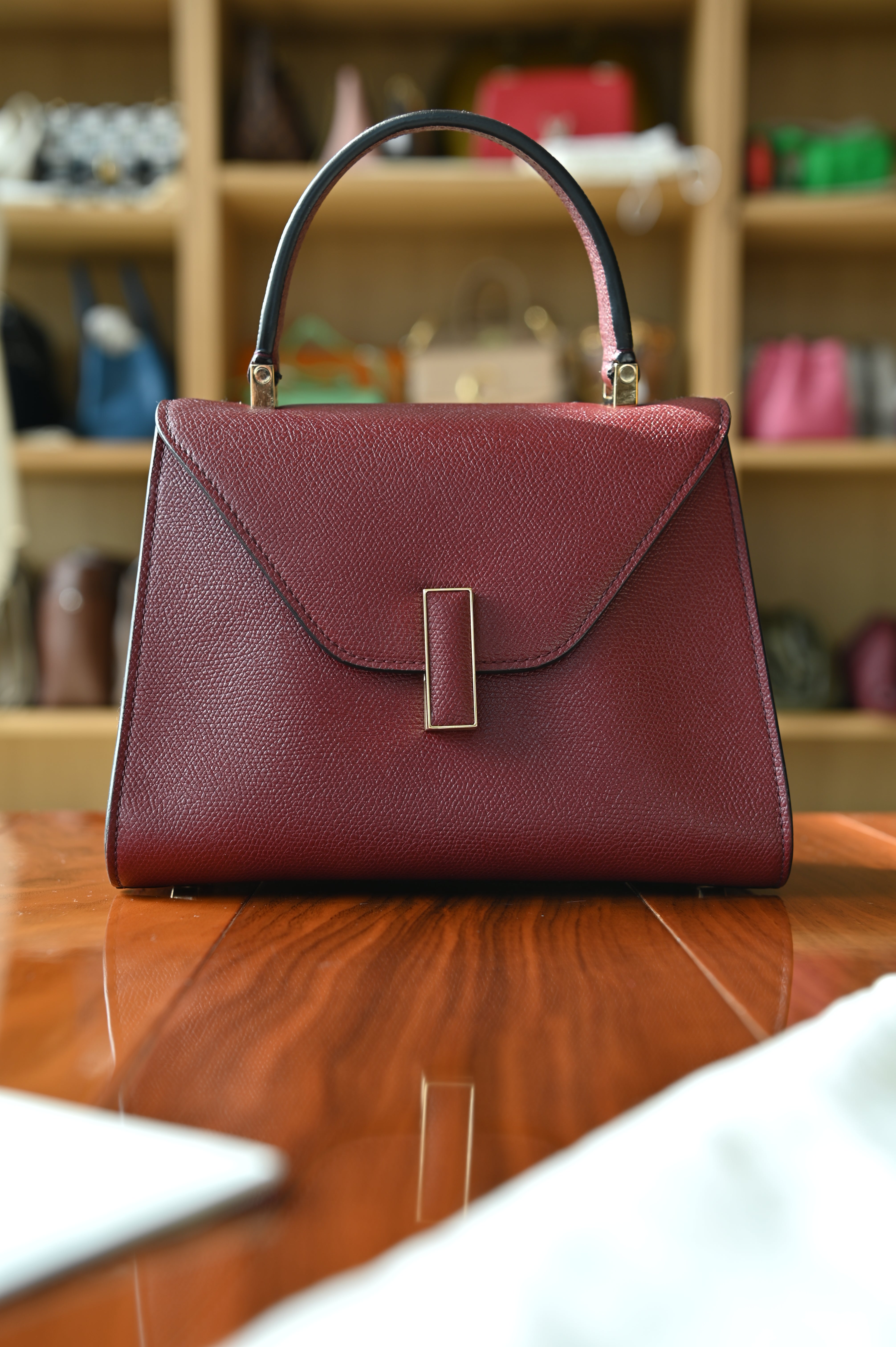Authentic Valextra Iside top handle bag in burgundy grained leather with signature V-shaped closure and gold-tone hardware.