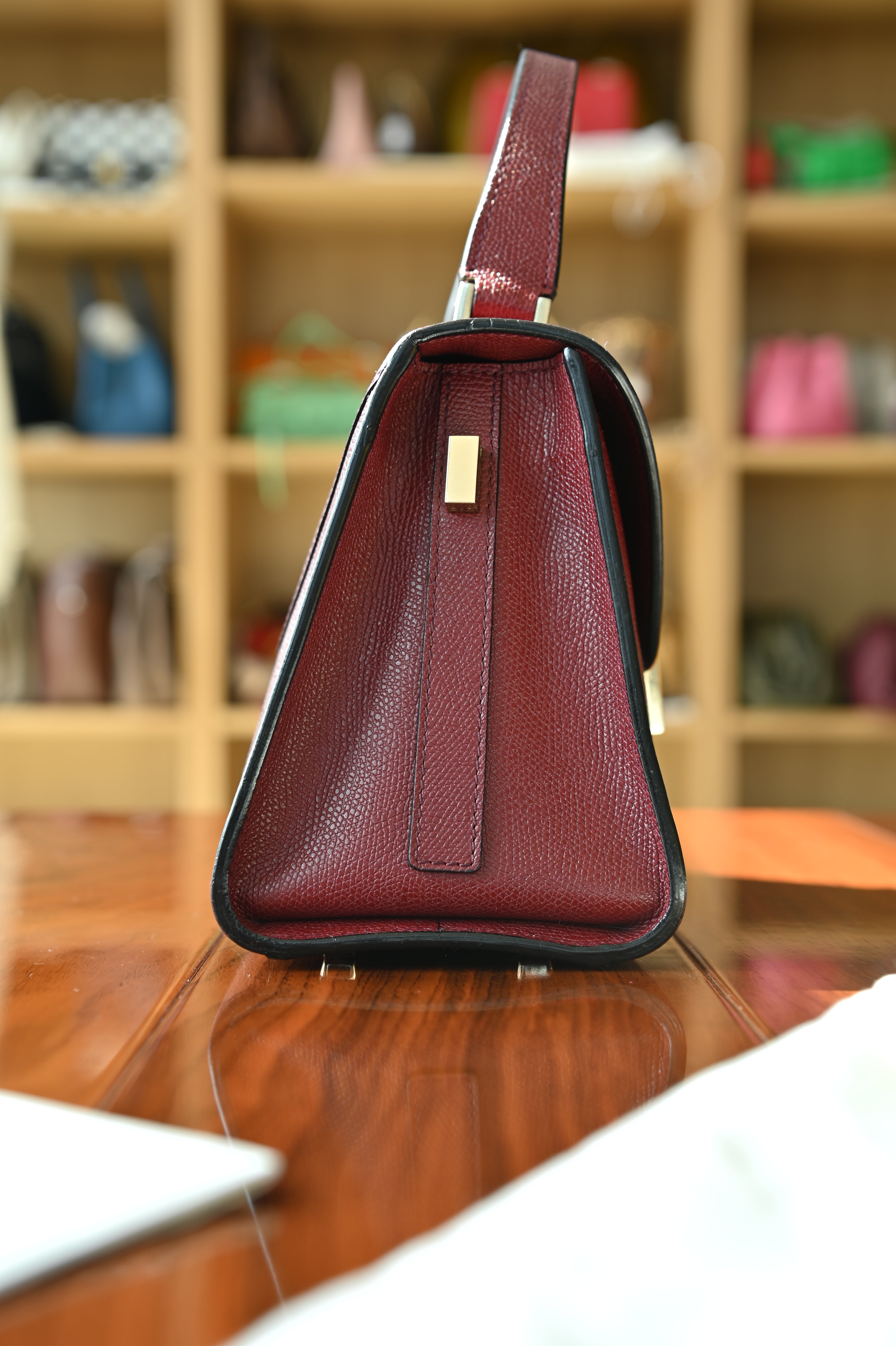 Right side profile of the authentic Valextra Iside handbag featuring its elegant structured design and gold-tone hardware.